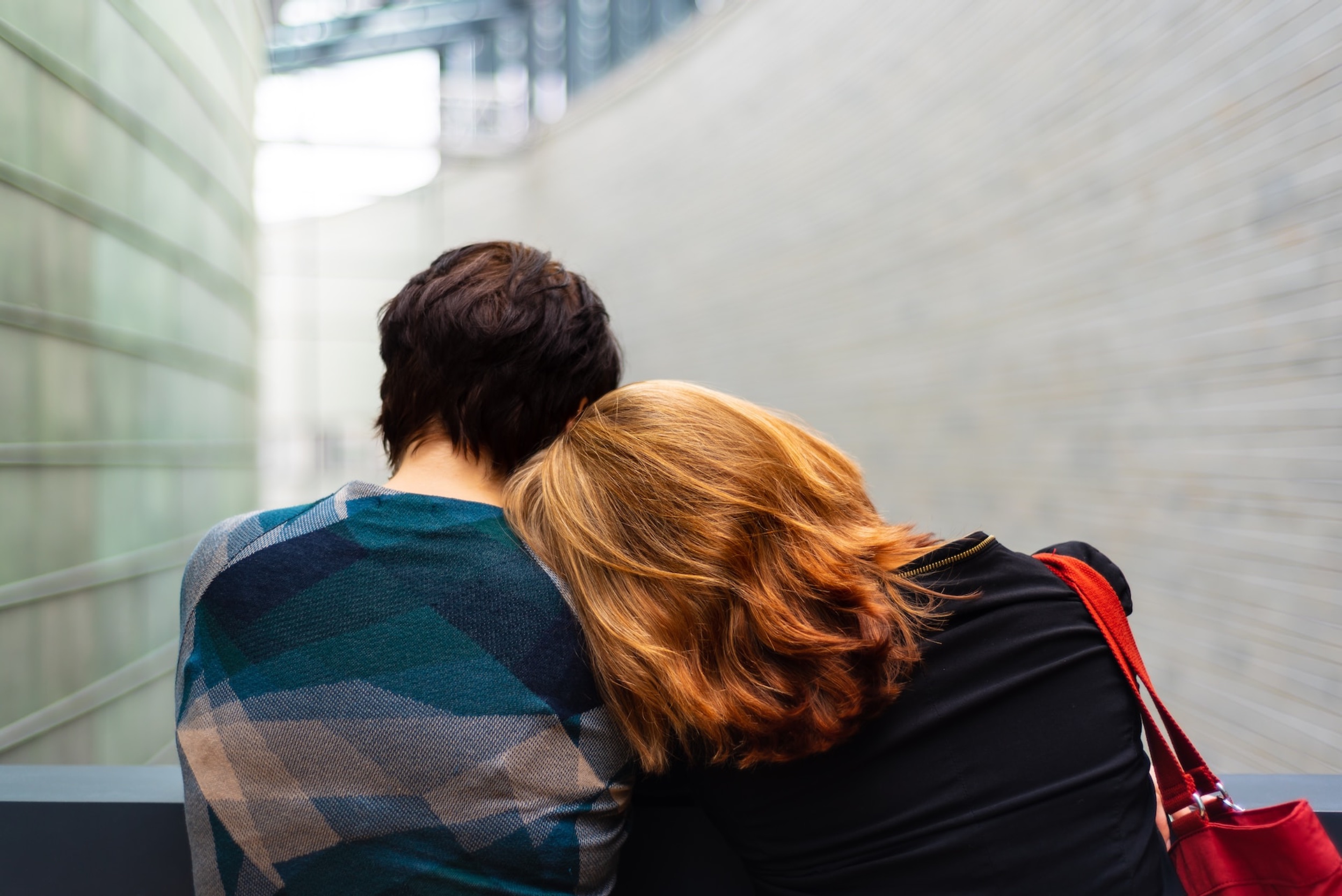A woman leans on a stranger's shoulder