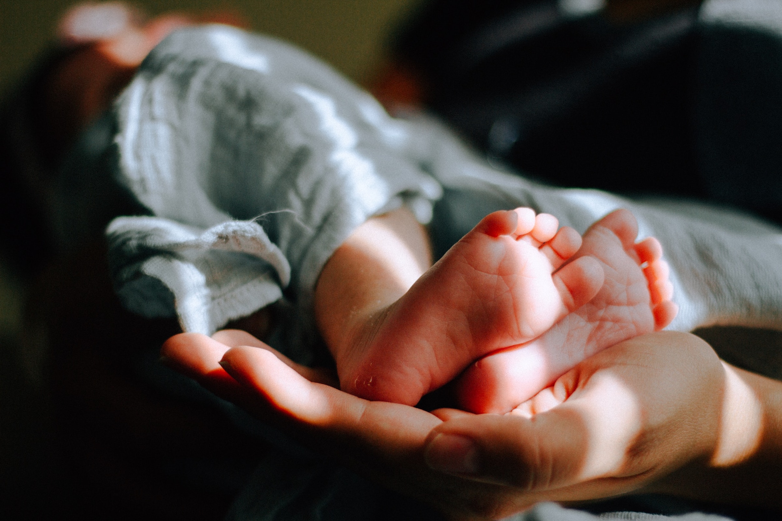 A woman cradles a baby's feet in her hand.