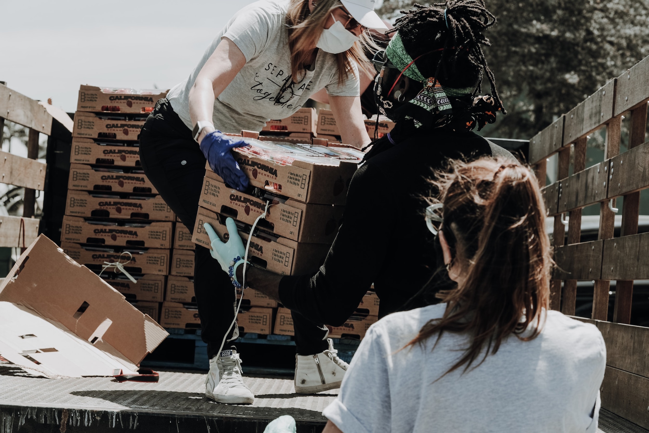 A group of volunteers carry boxes out of an oversized truck.