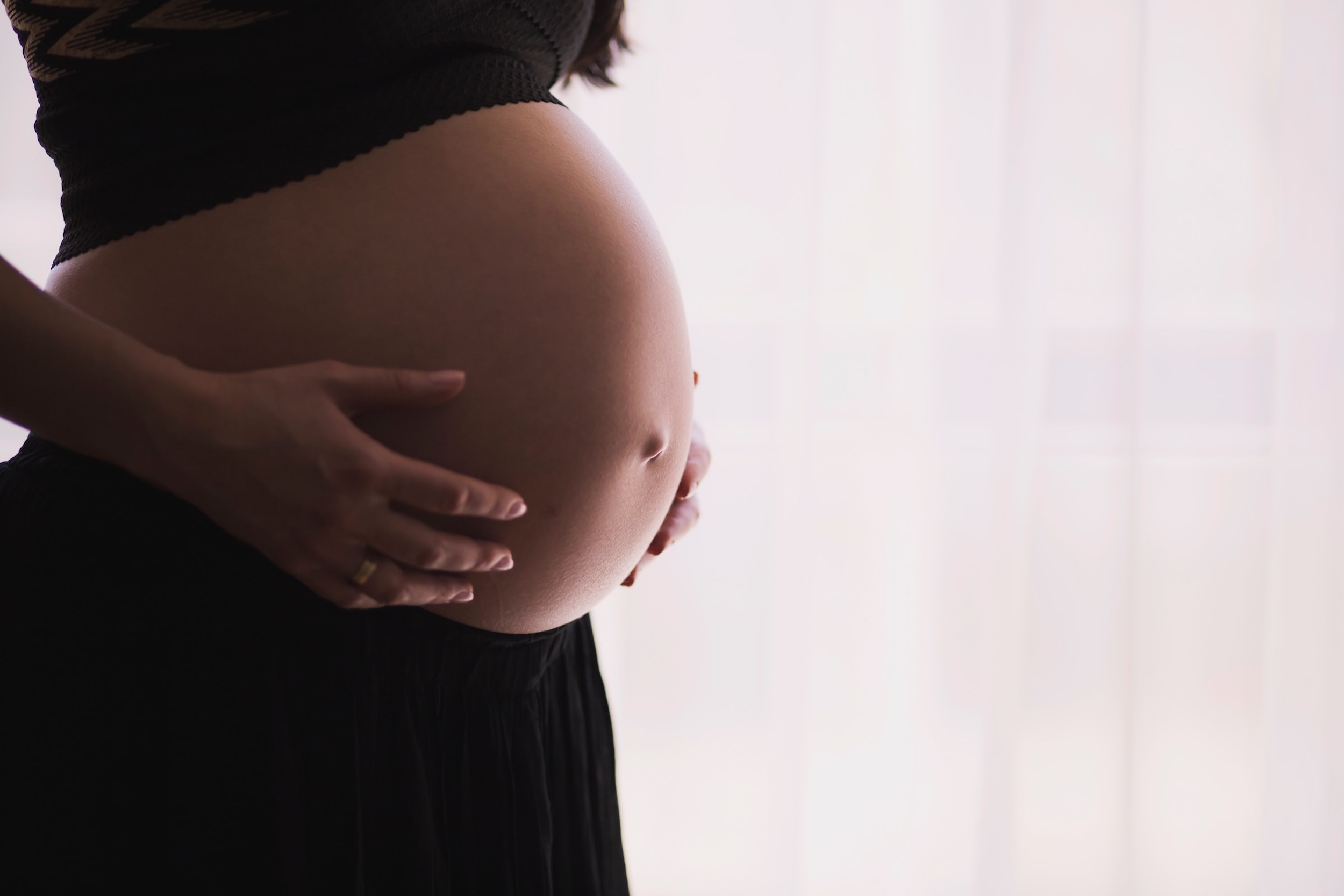 A pregnant woman clutches the sides of her belly.