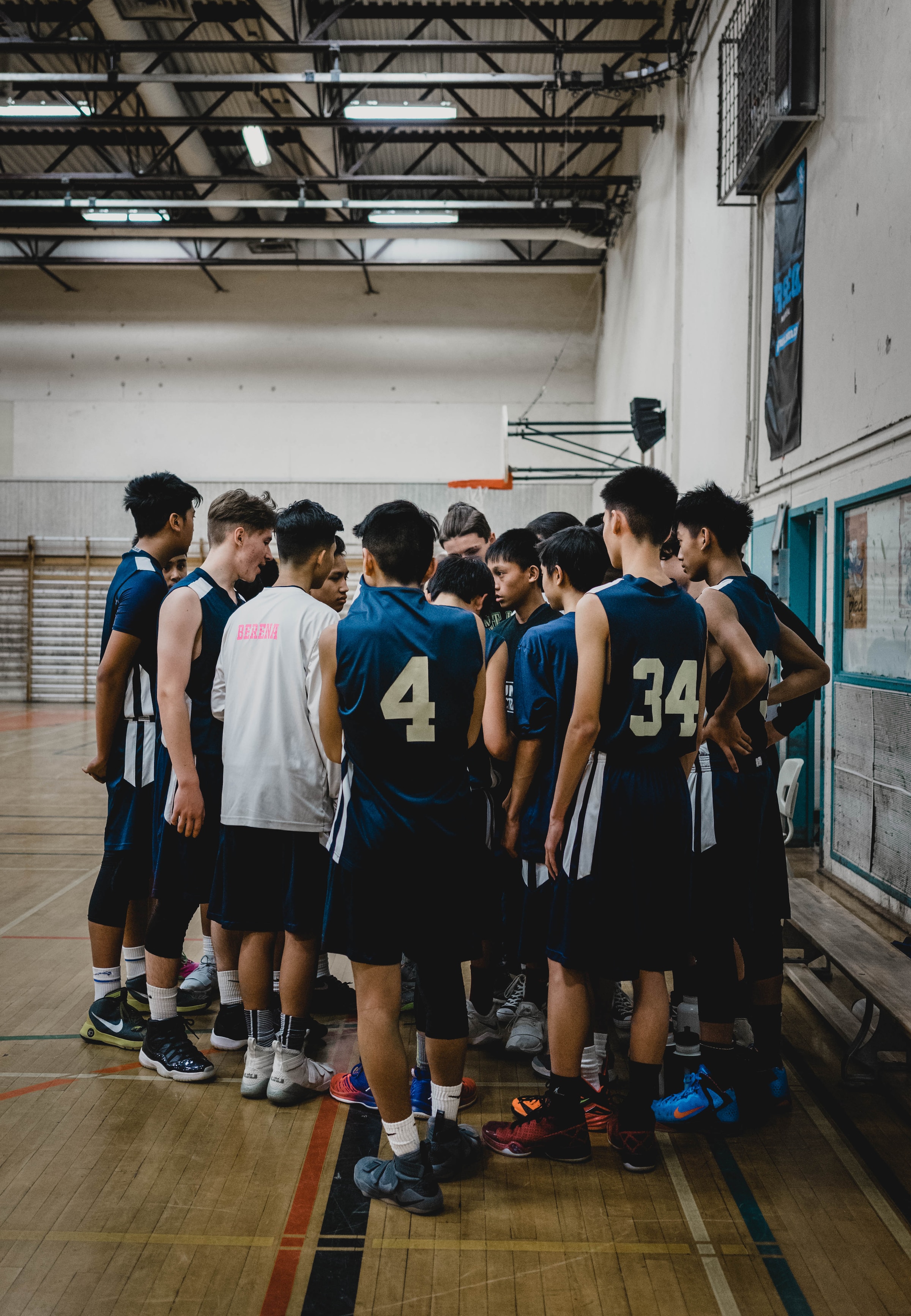 A group of teens huddle together on a basketball court.