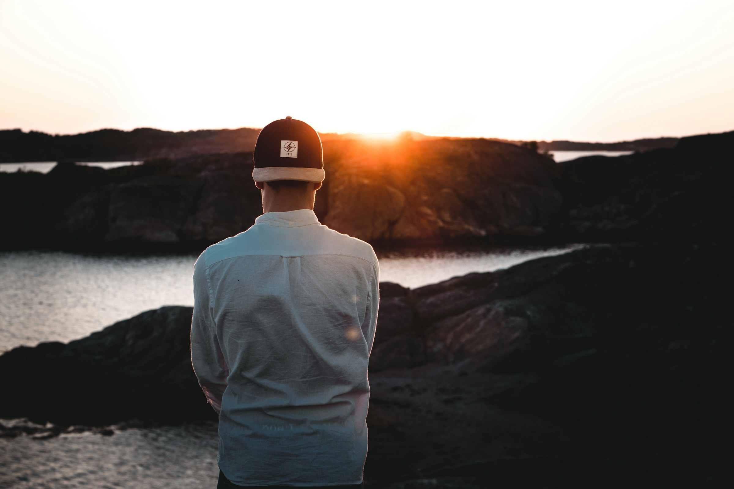 A man stands near the ocean with his arms crossed.