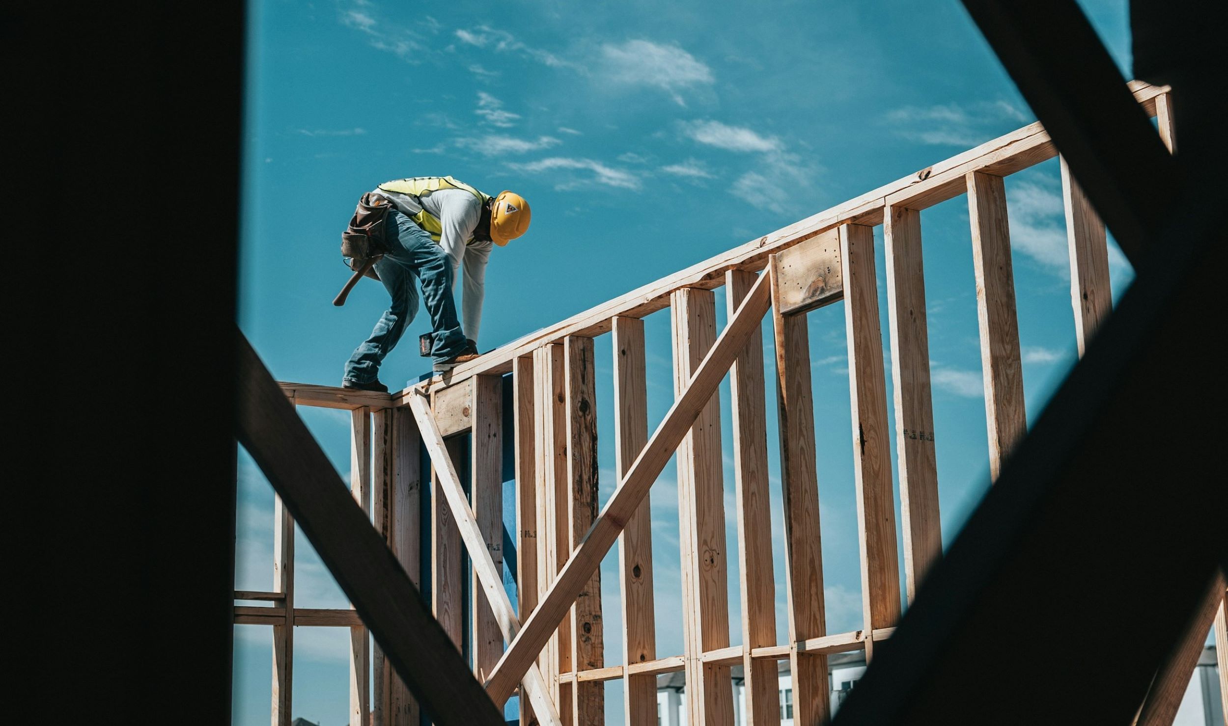 A construction worker stands on a wooden board and builds a house.