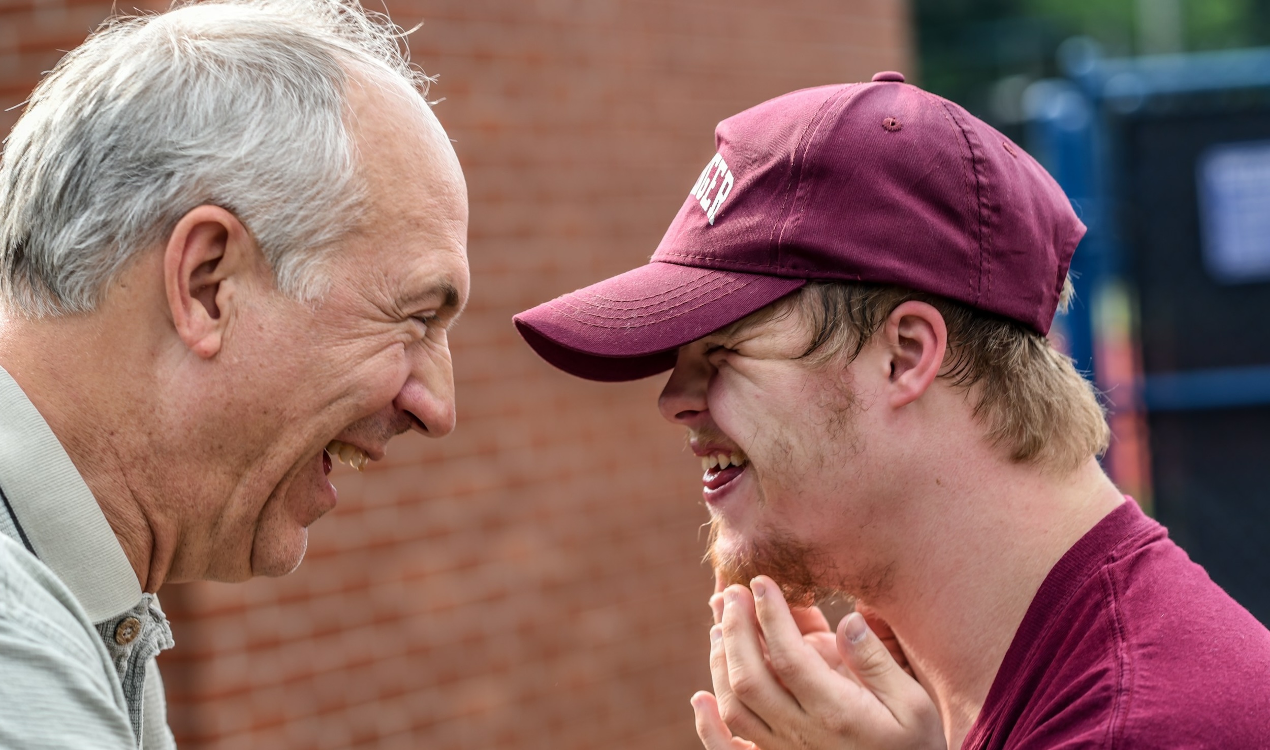 An elderly man and a boy smile at each other.