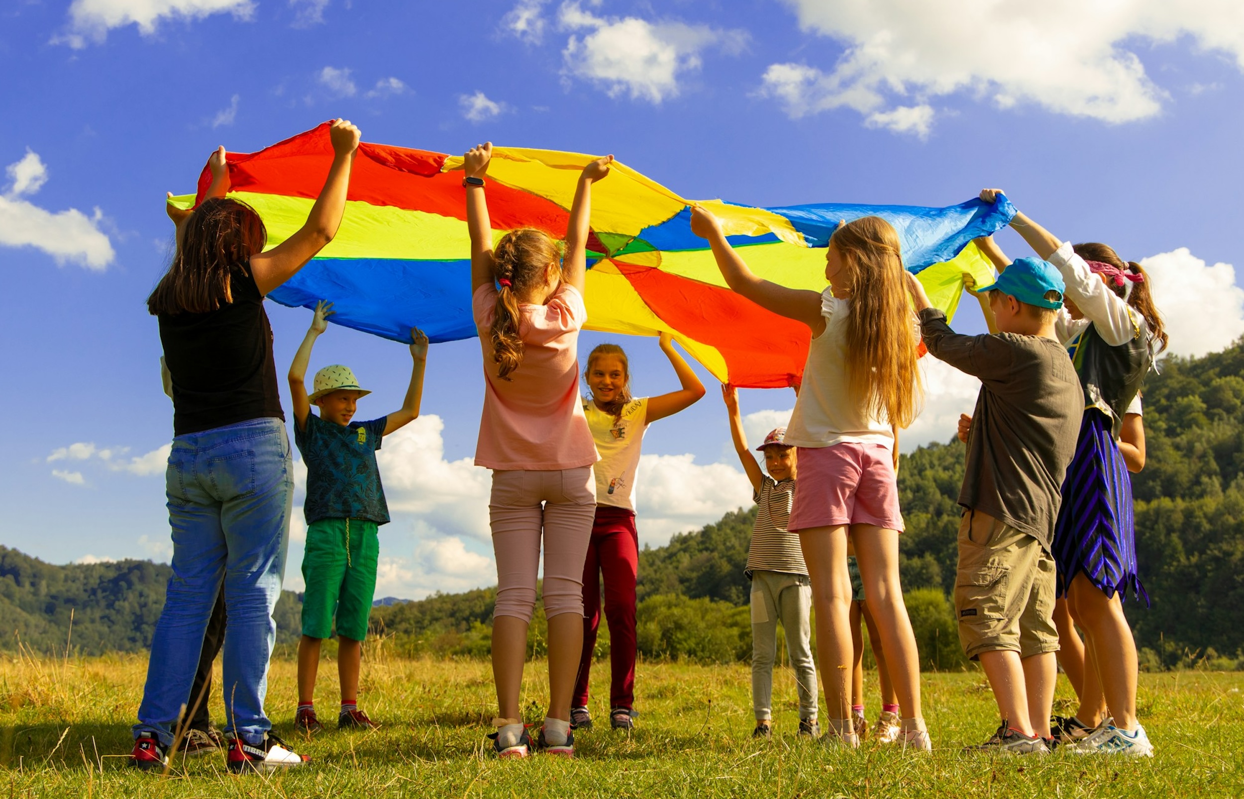 A group of kids lift a colorful sheet.