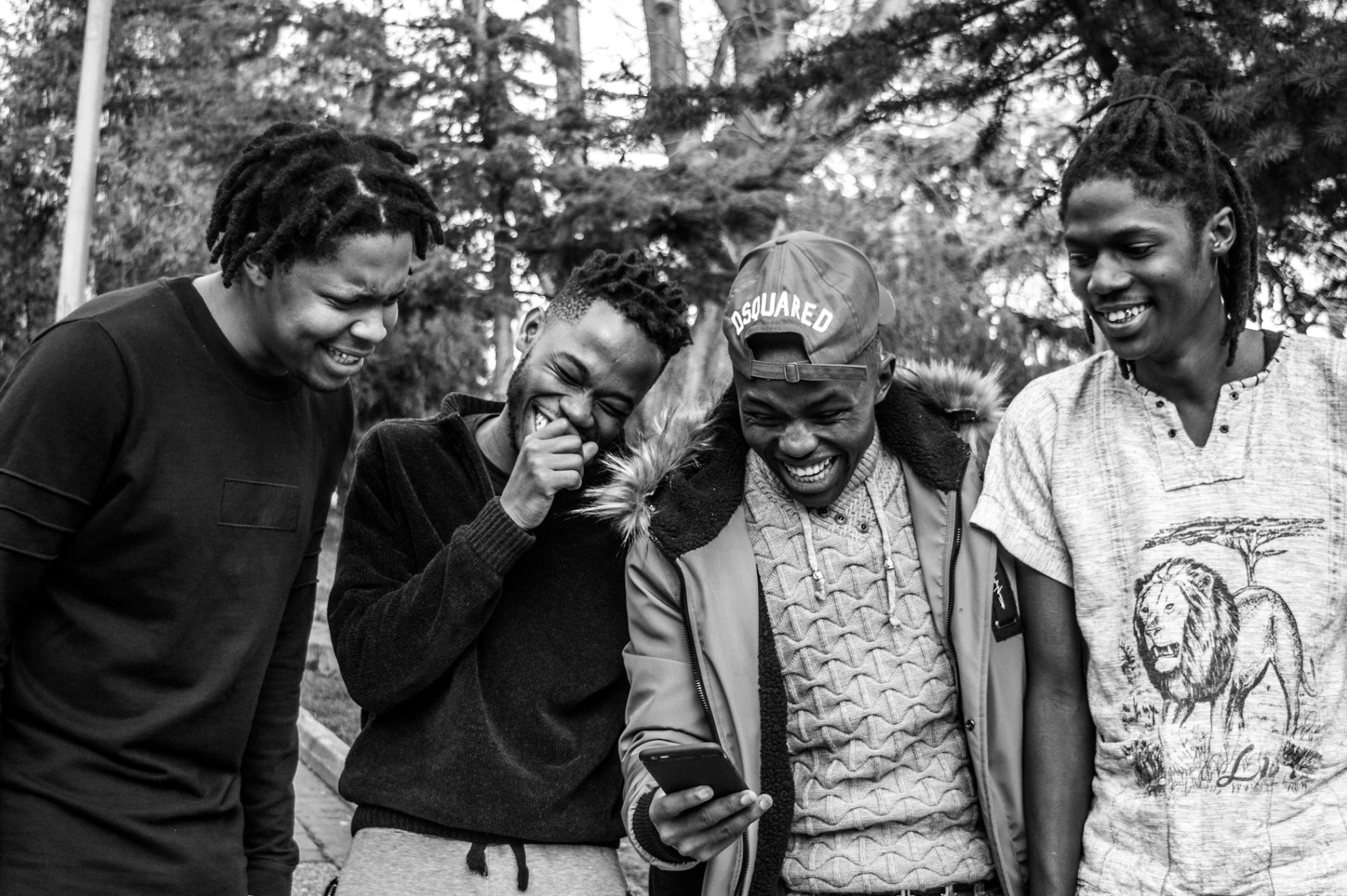 A group of African American men laugh and huddle together.