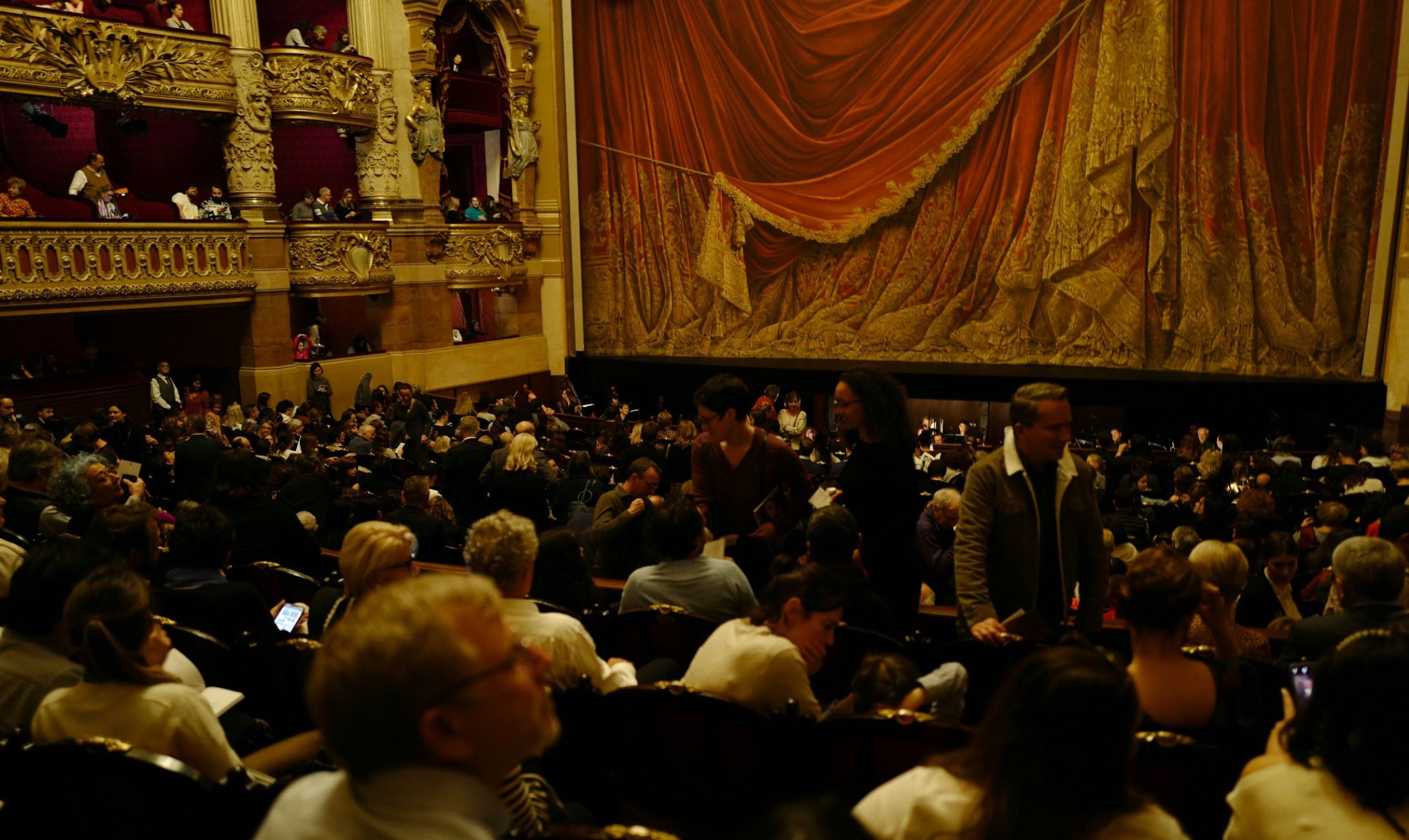A large audience sits in front of an opera stage.