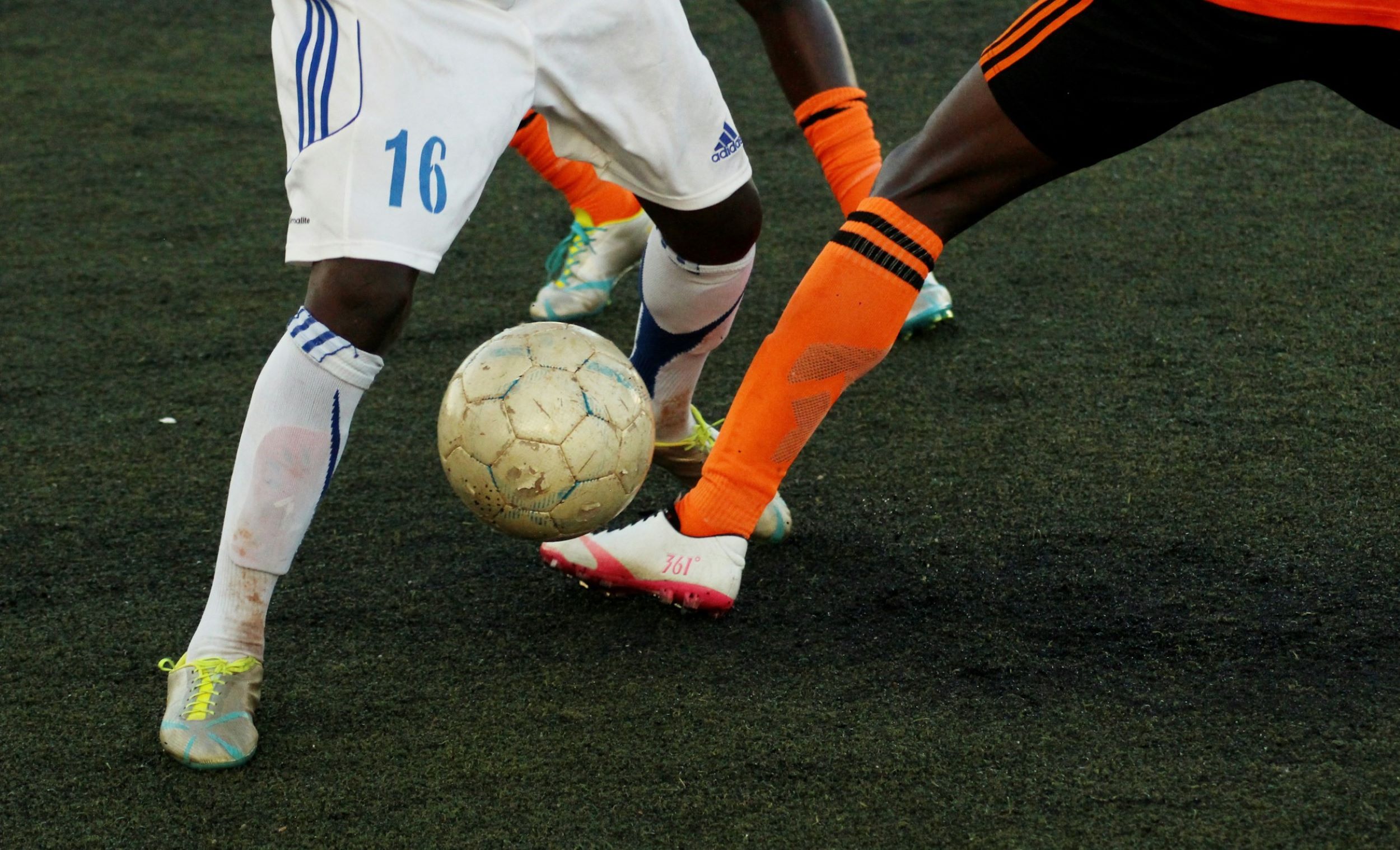 Two athletes play soccer and contend for the ball.