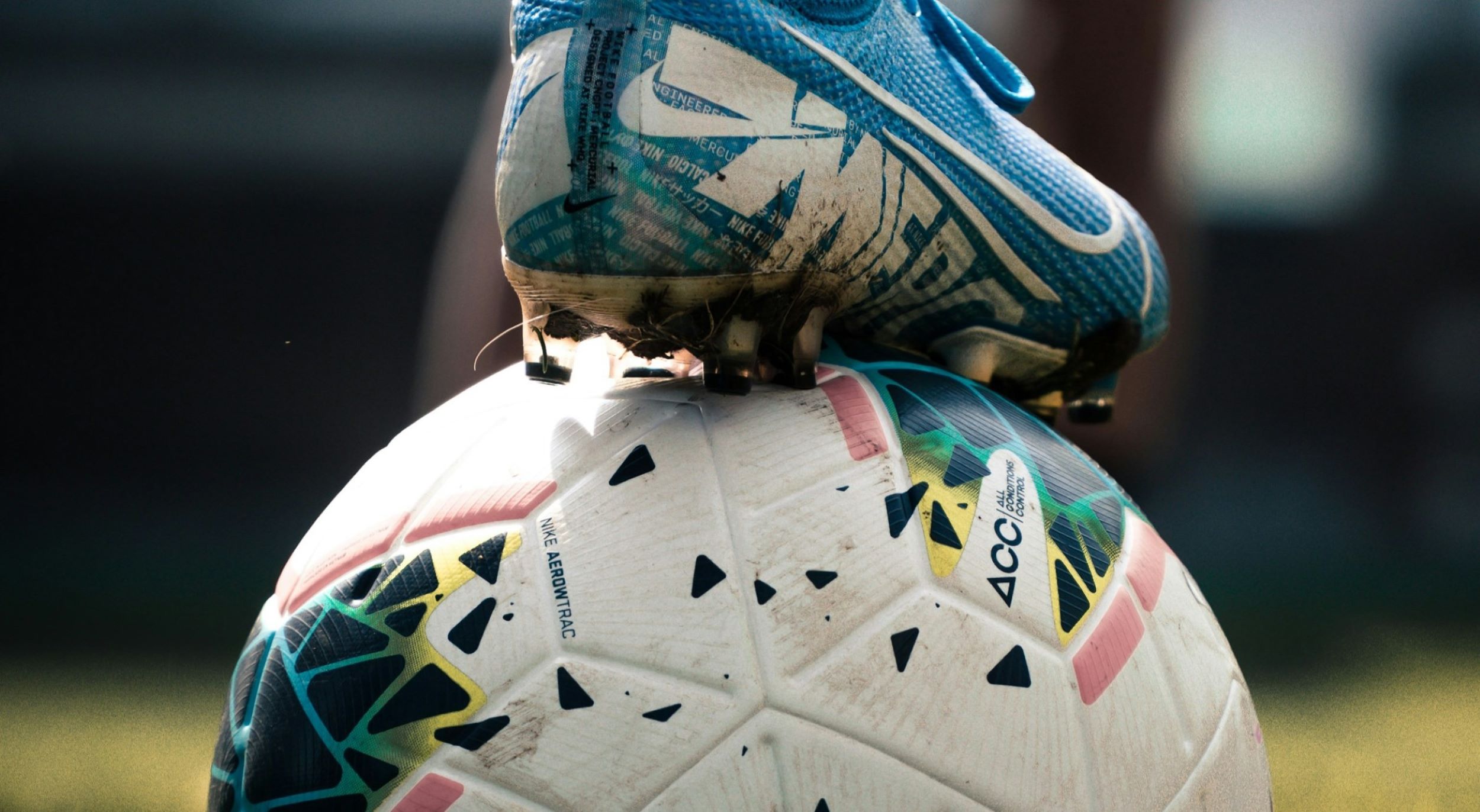 A foot stands on a white soccer ball.