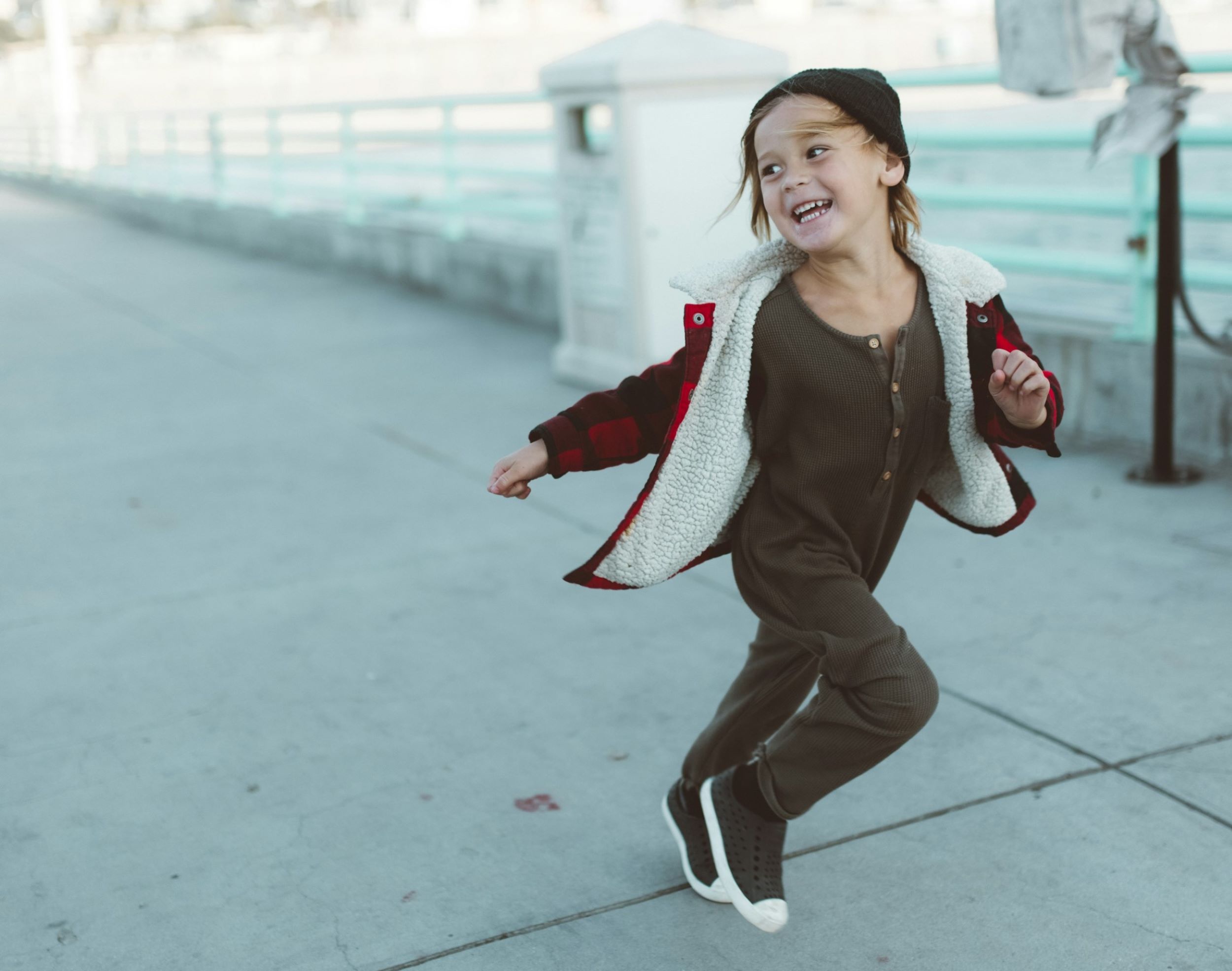 A child smiles and runs on a boardwalk.