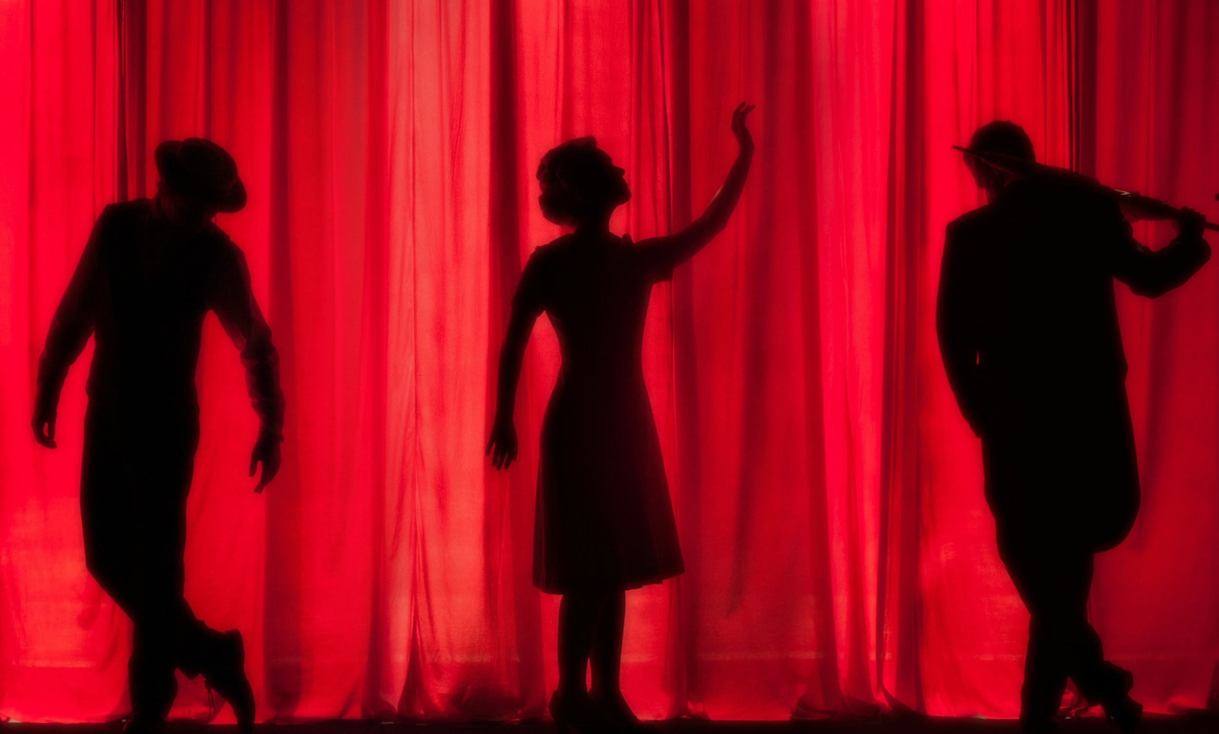 Two actors and a musician pose in dramatic positions.