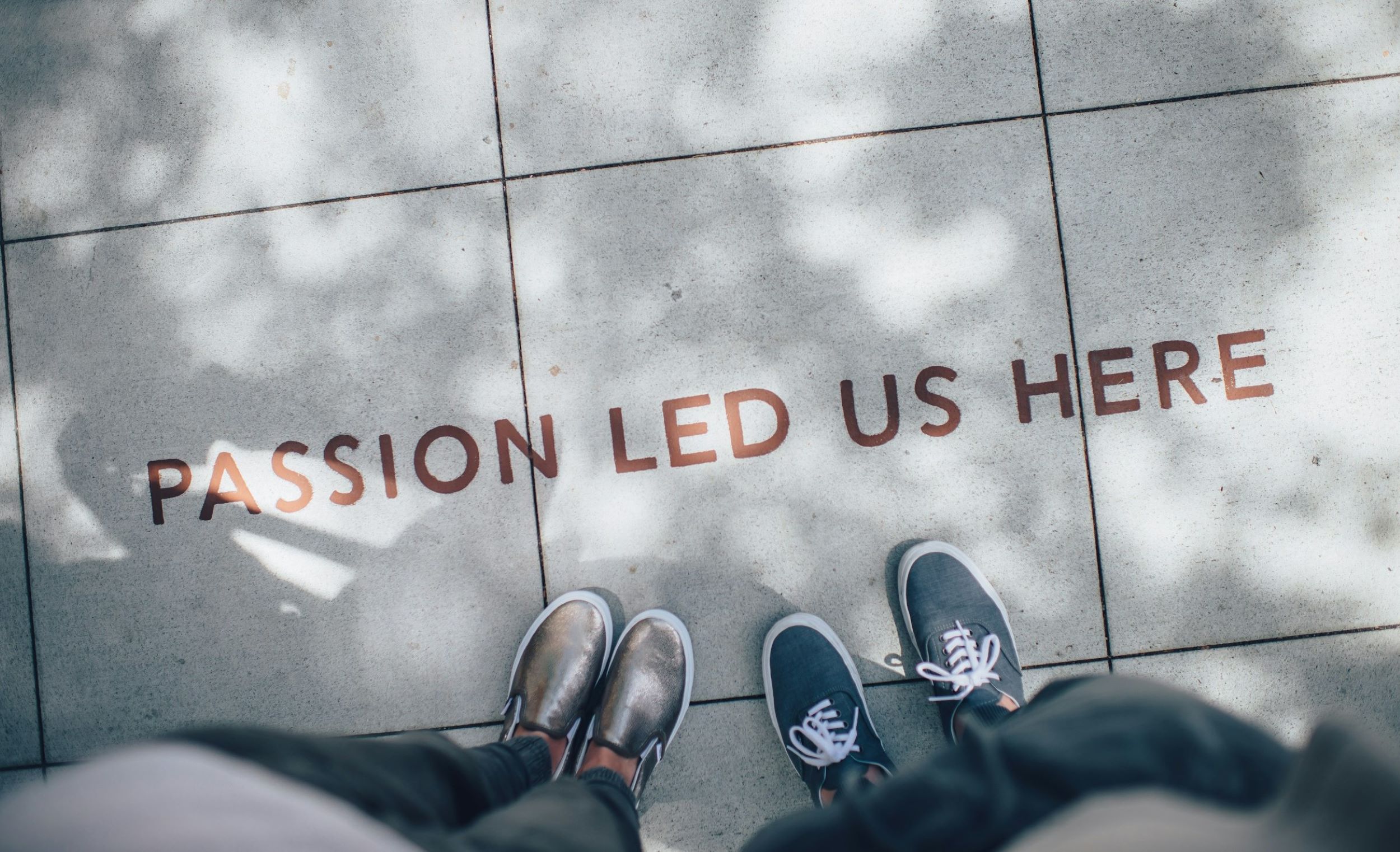 Feet stand in front of a small quote on a concrete floor.