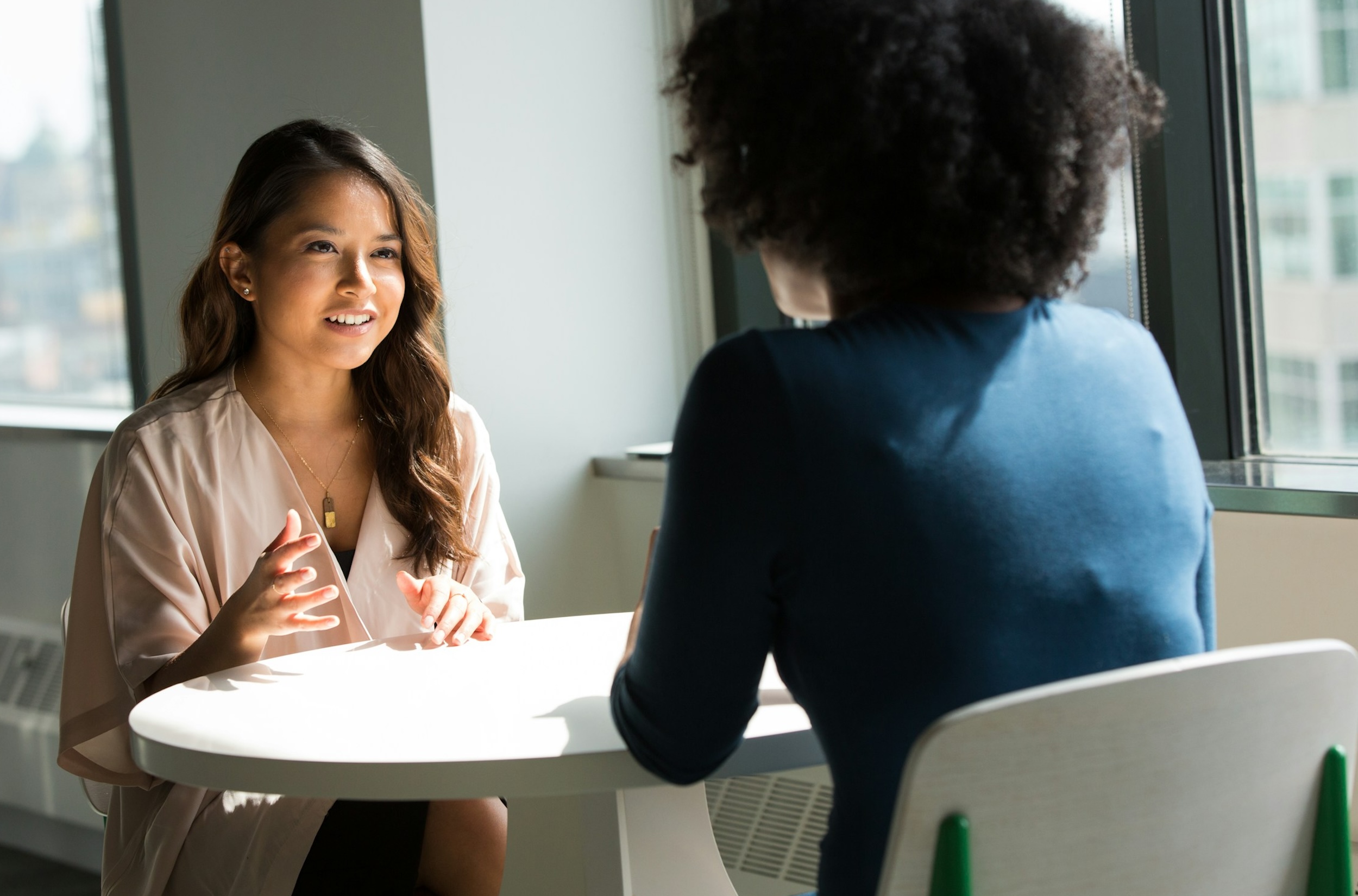Two women speak at a table.