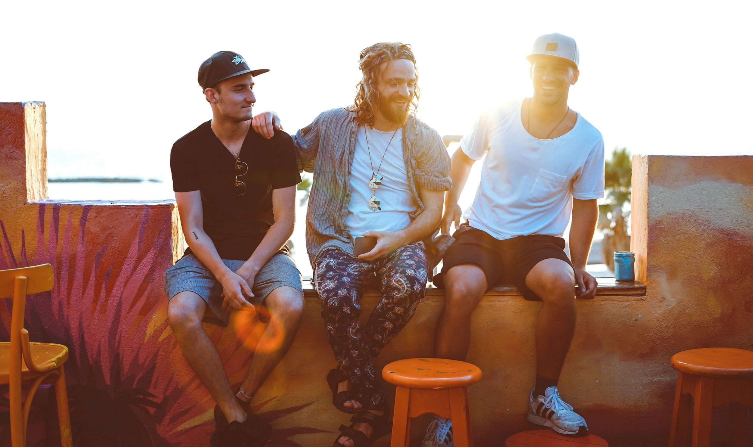 Three men pose with sunlight from the horizon as their backdrop.