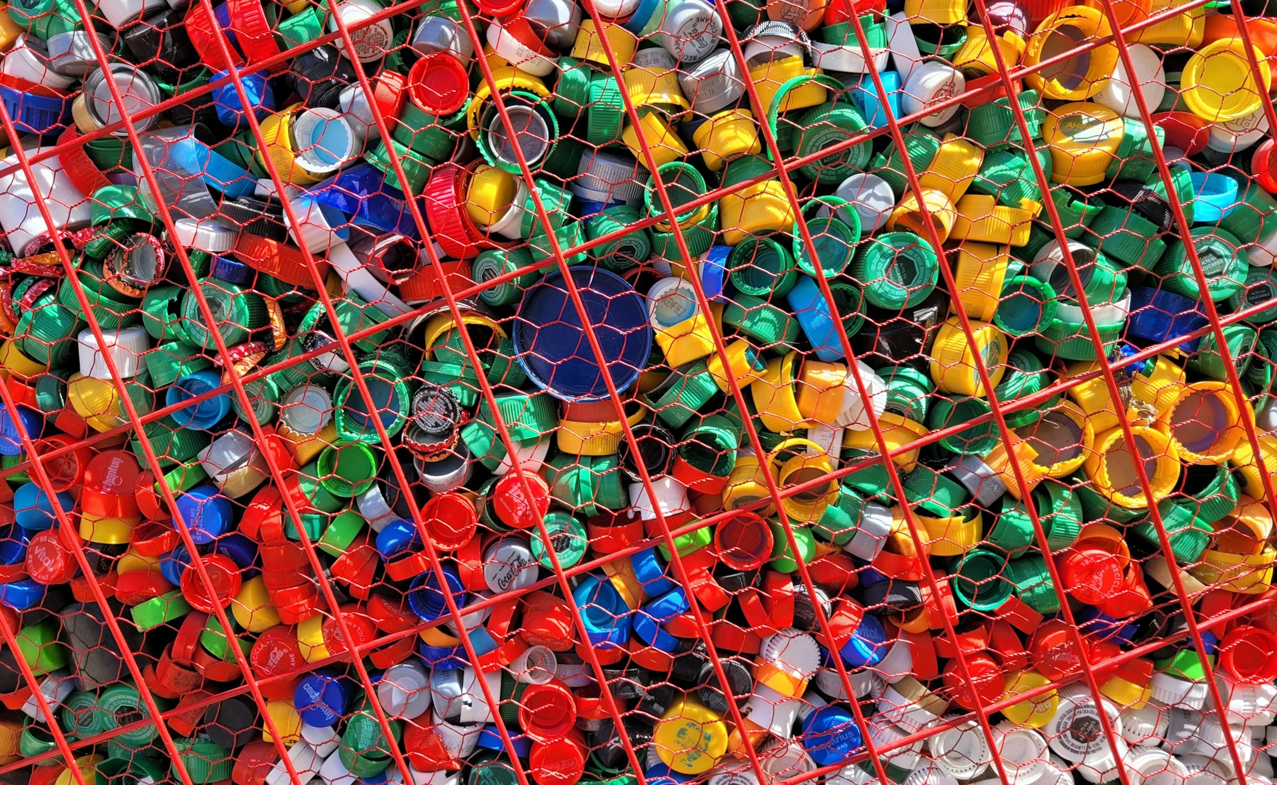Cans of different colors and shapes are crammed into a red net.