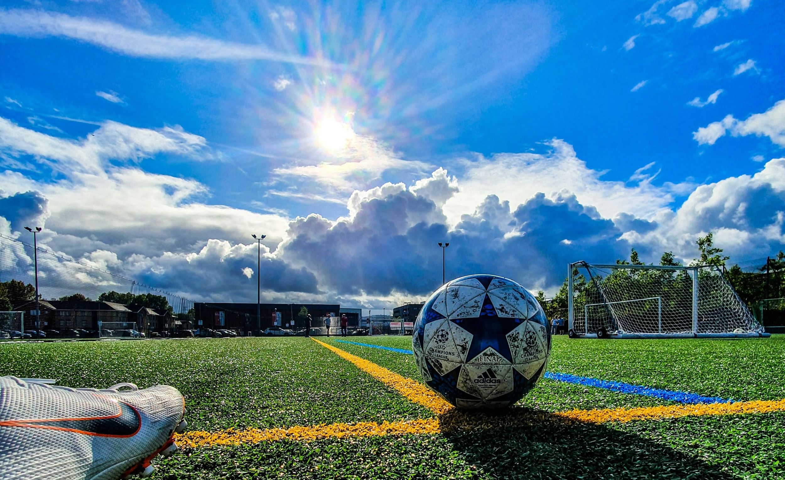 A soccer player places his foot near a soccer ball on a field.
