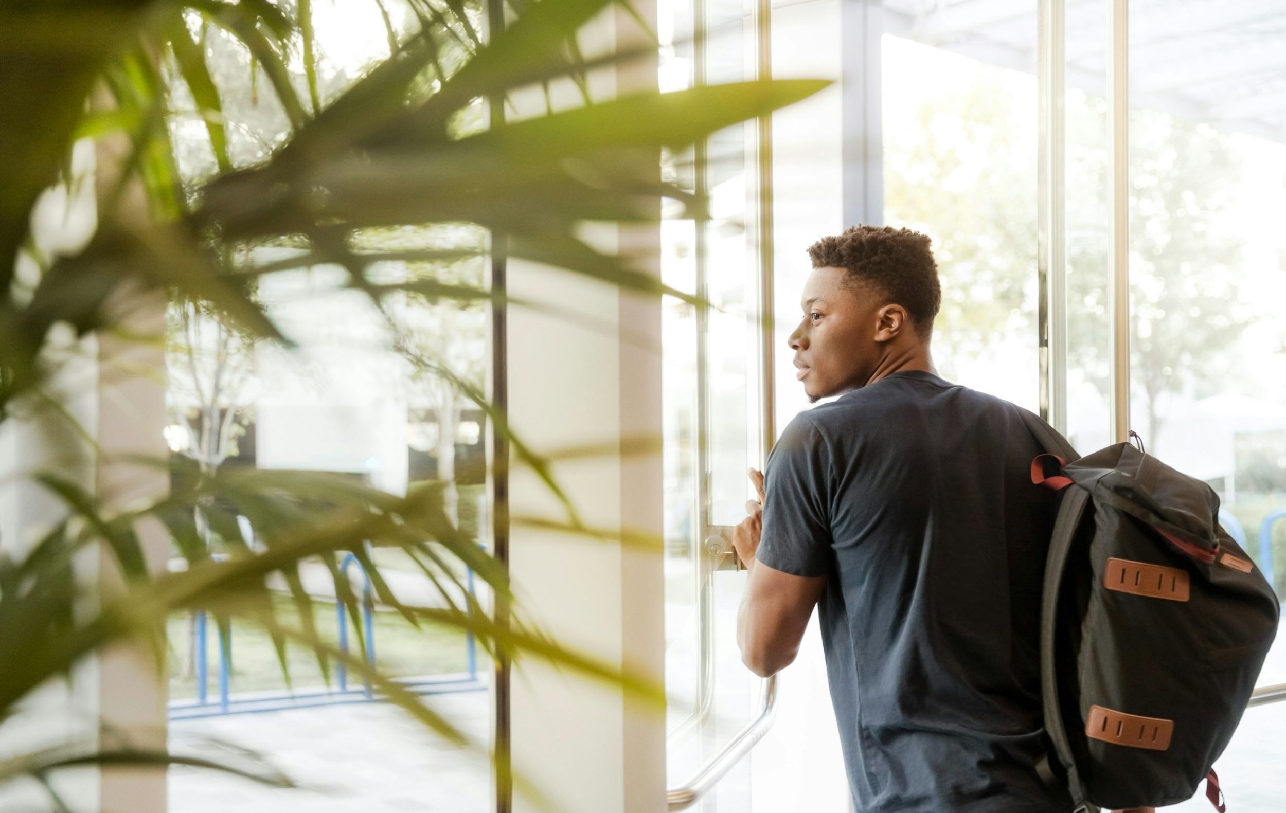 A student carries a black backpack while exiting a building.