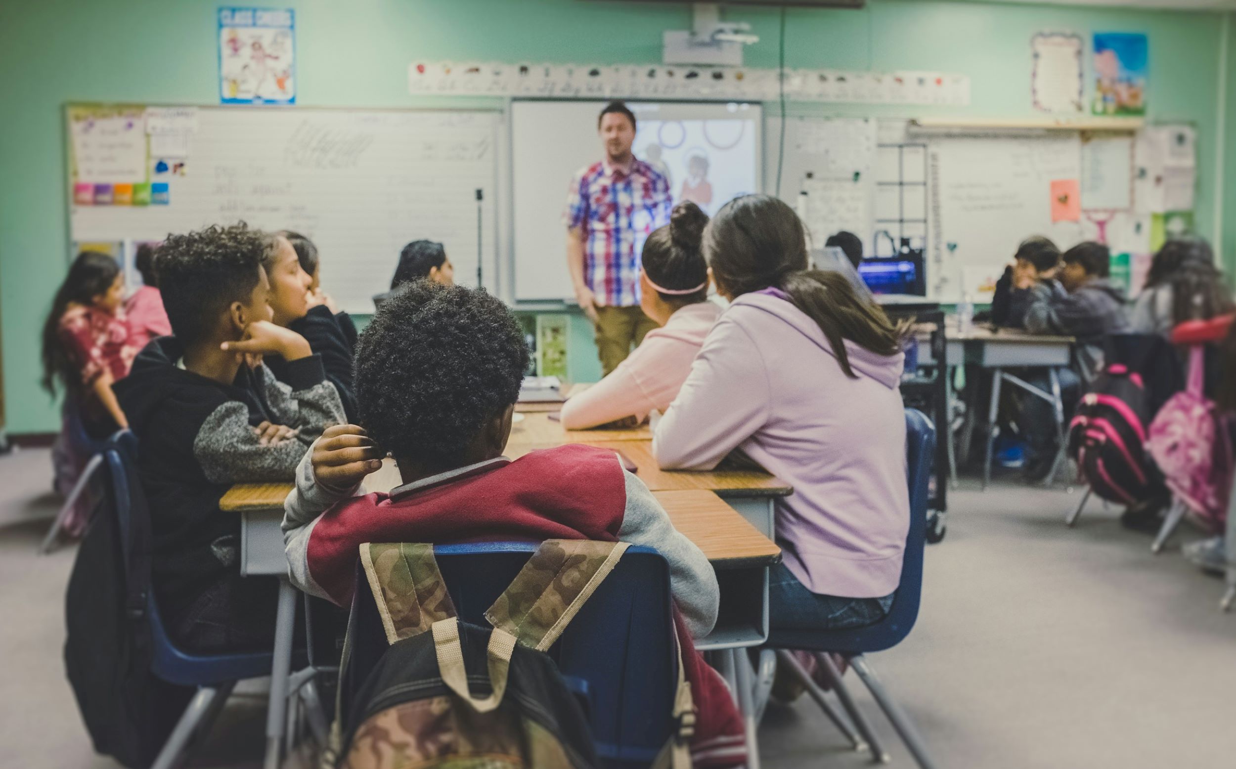 A teacher speaks with students in a classroom.