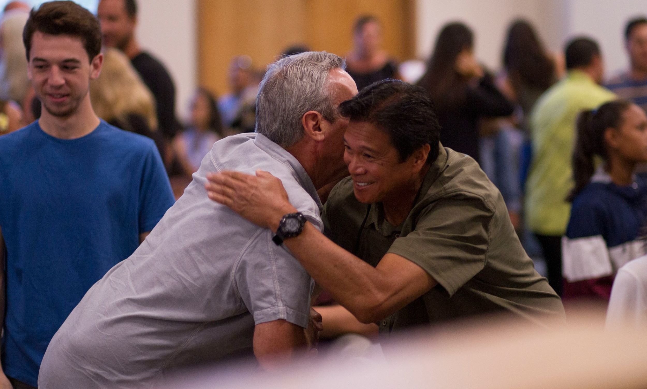 Two men smile while embracing each other.
