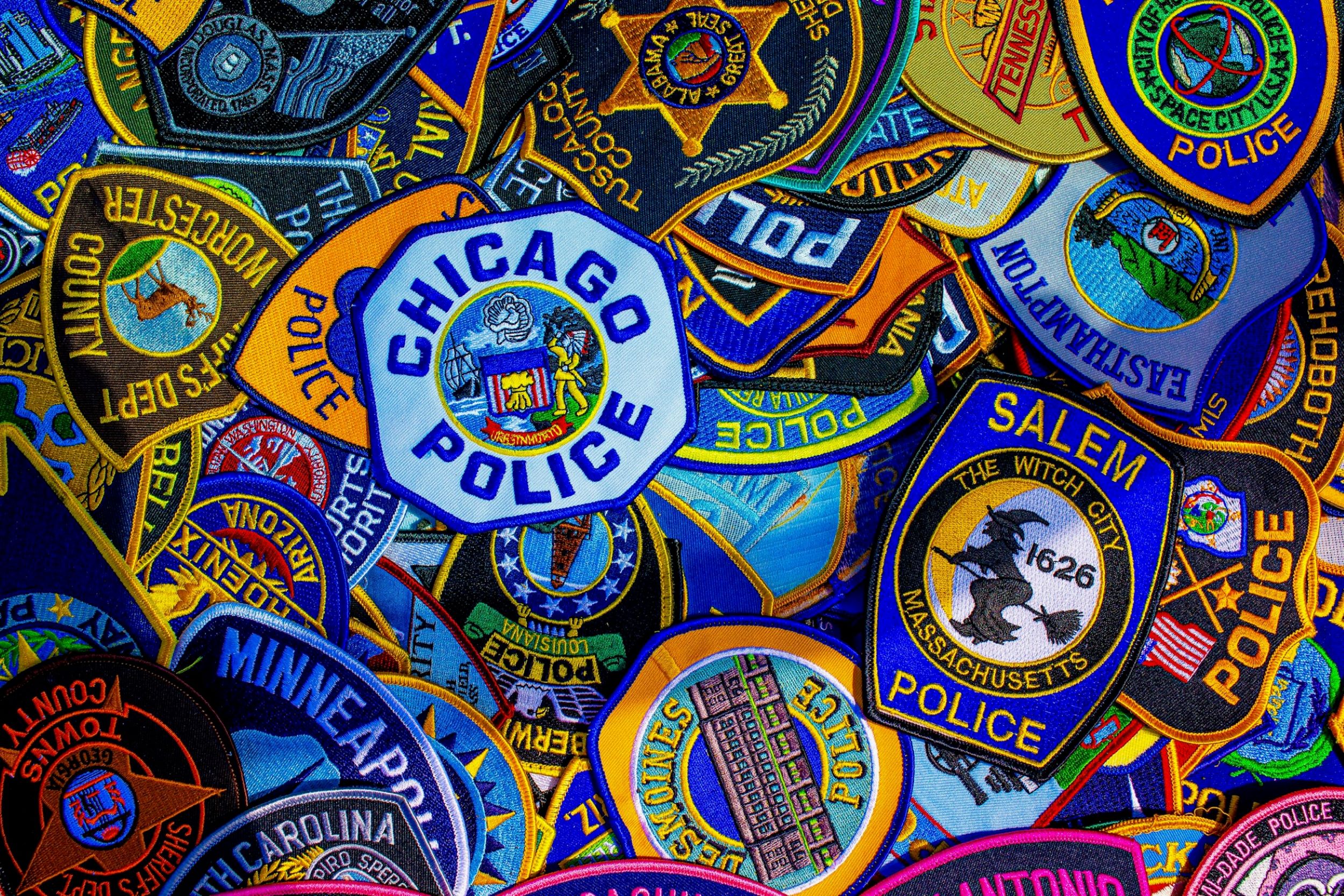 An assortment of colorful police badges are stacked on top of each other.