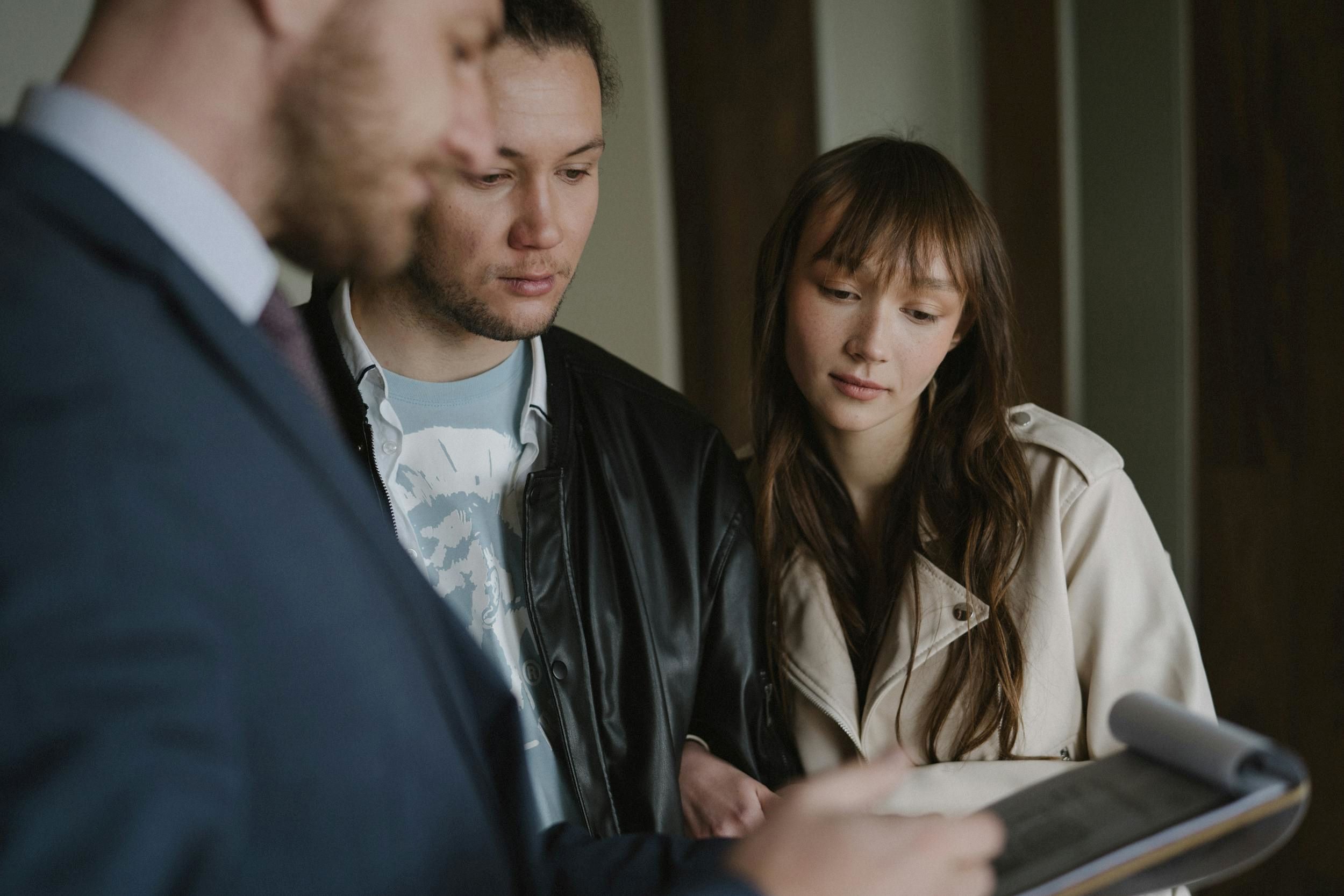 An agent and a couple review a contract together.
