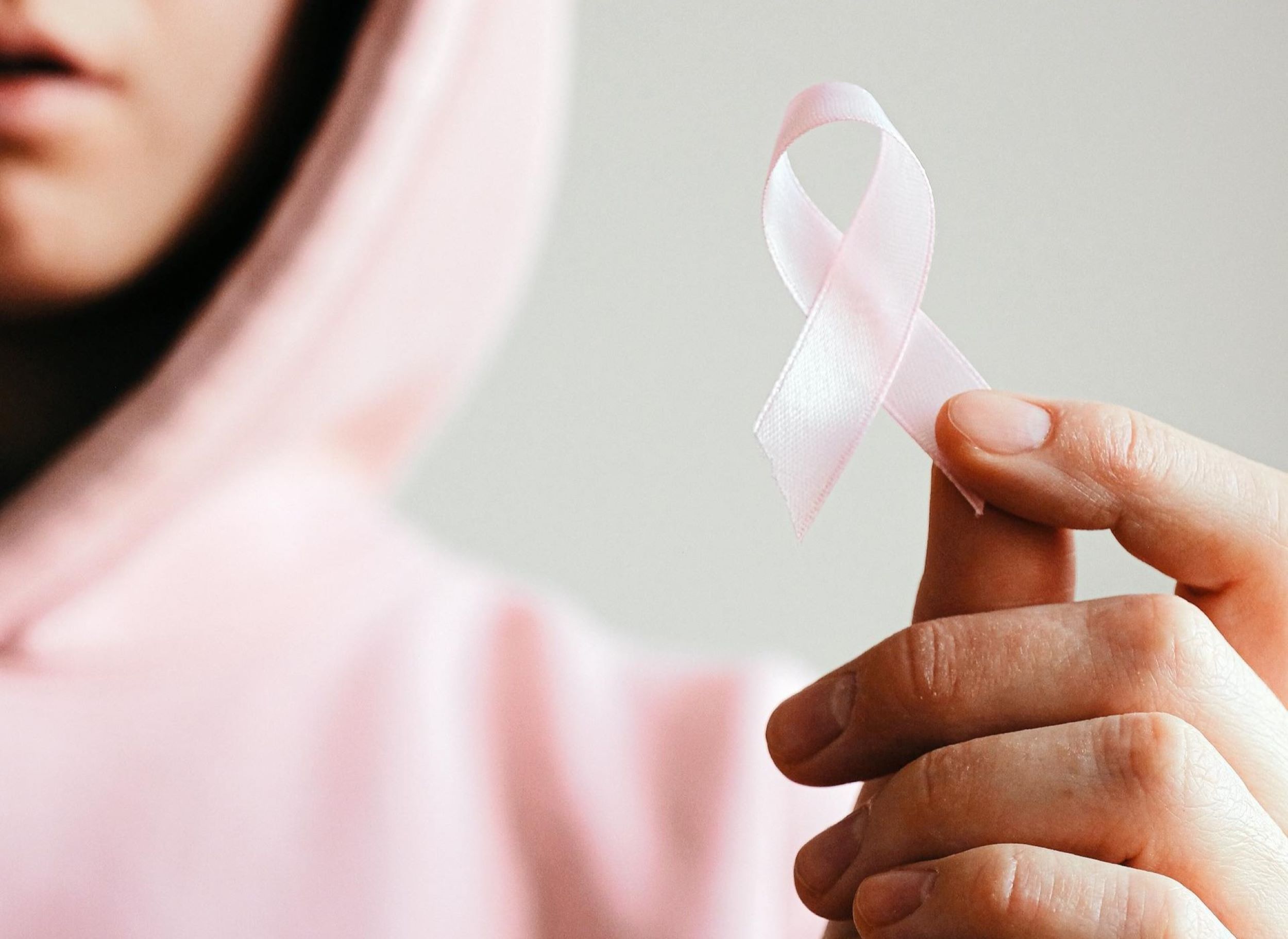 A woman holds a breast cancer ribbon.