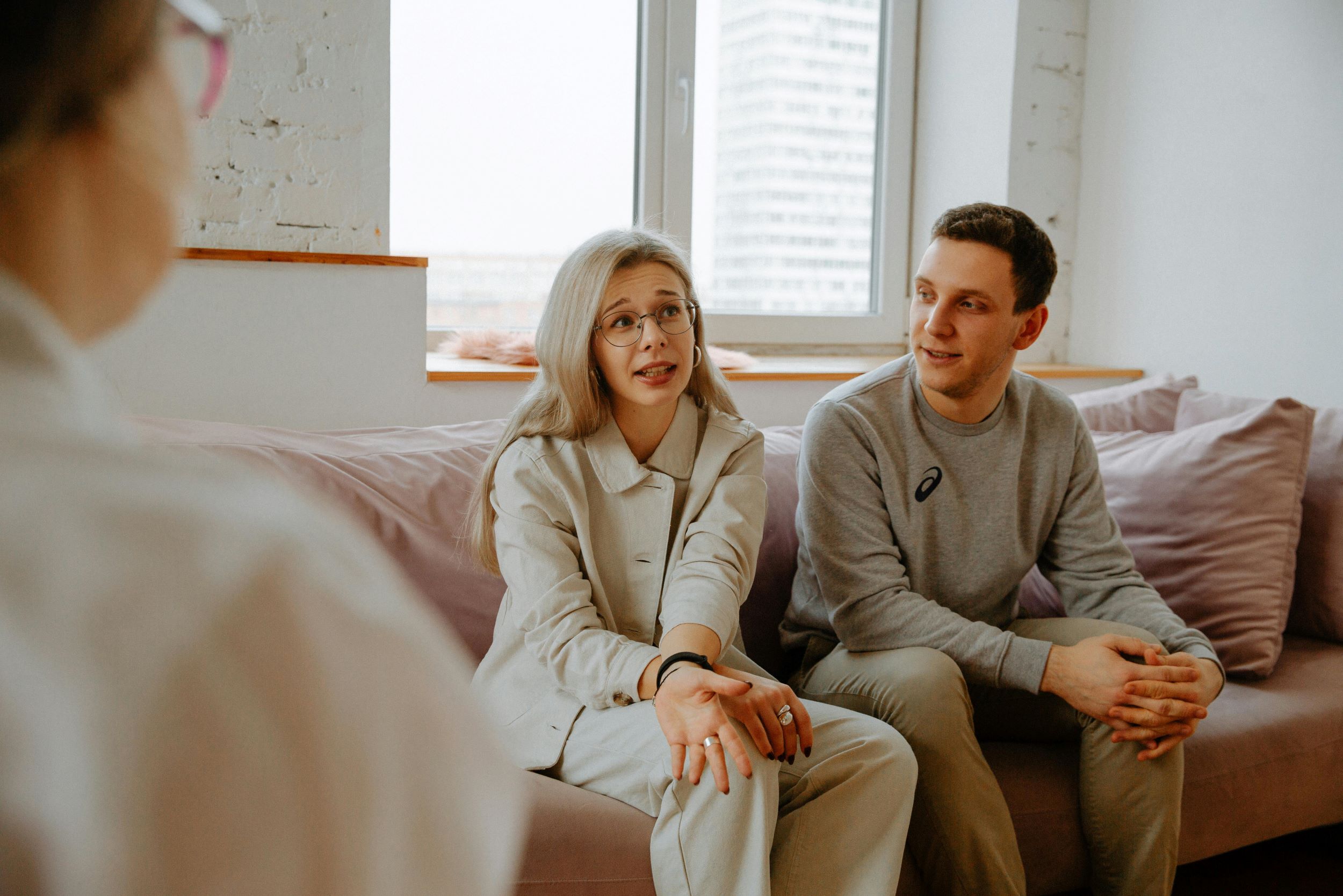 A therapist meets with two patients in a small room furnished in a minimalist style.