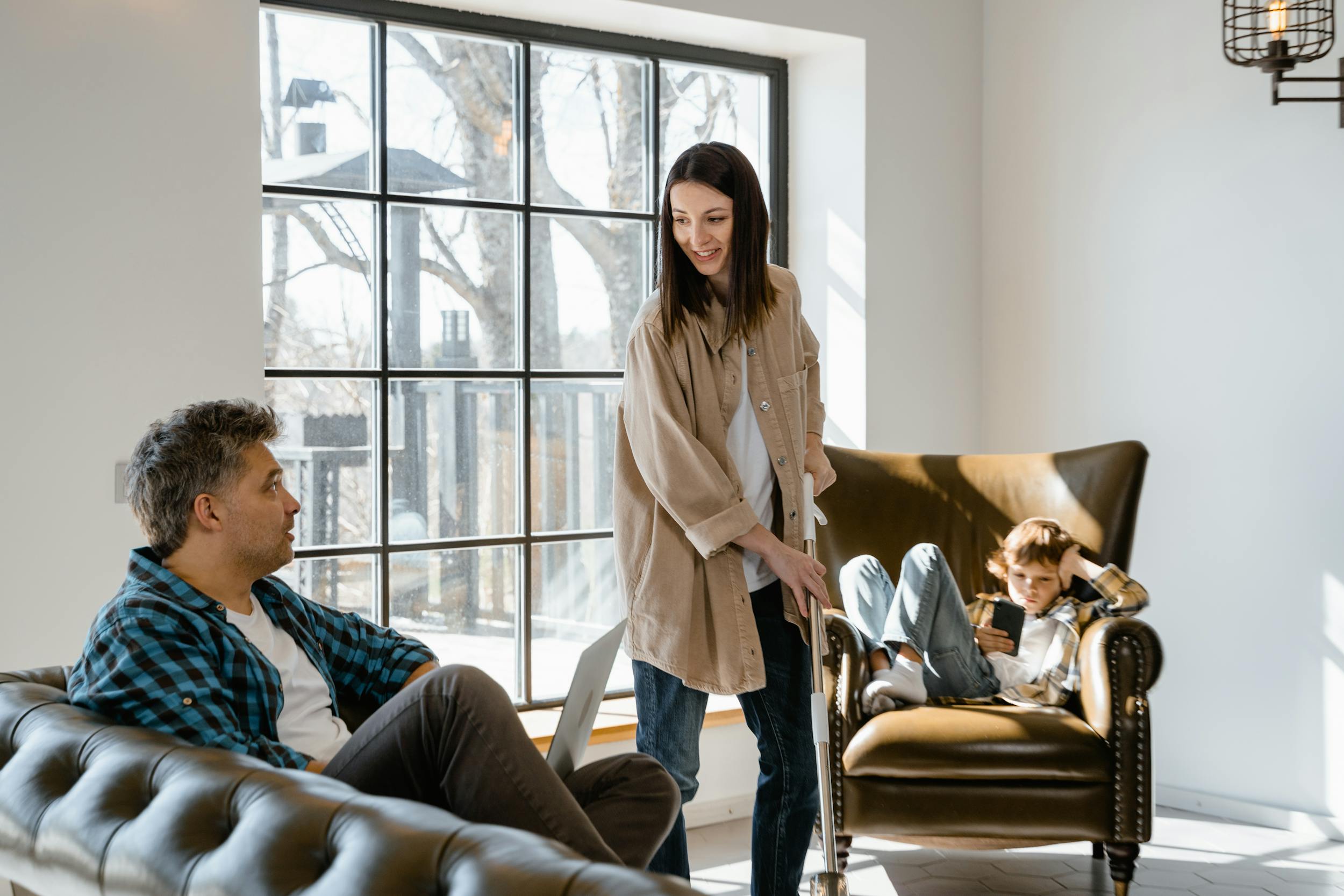 A family sits inside of an apartment with contemporary furniture.