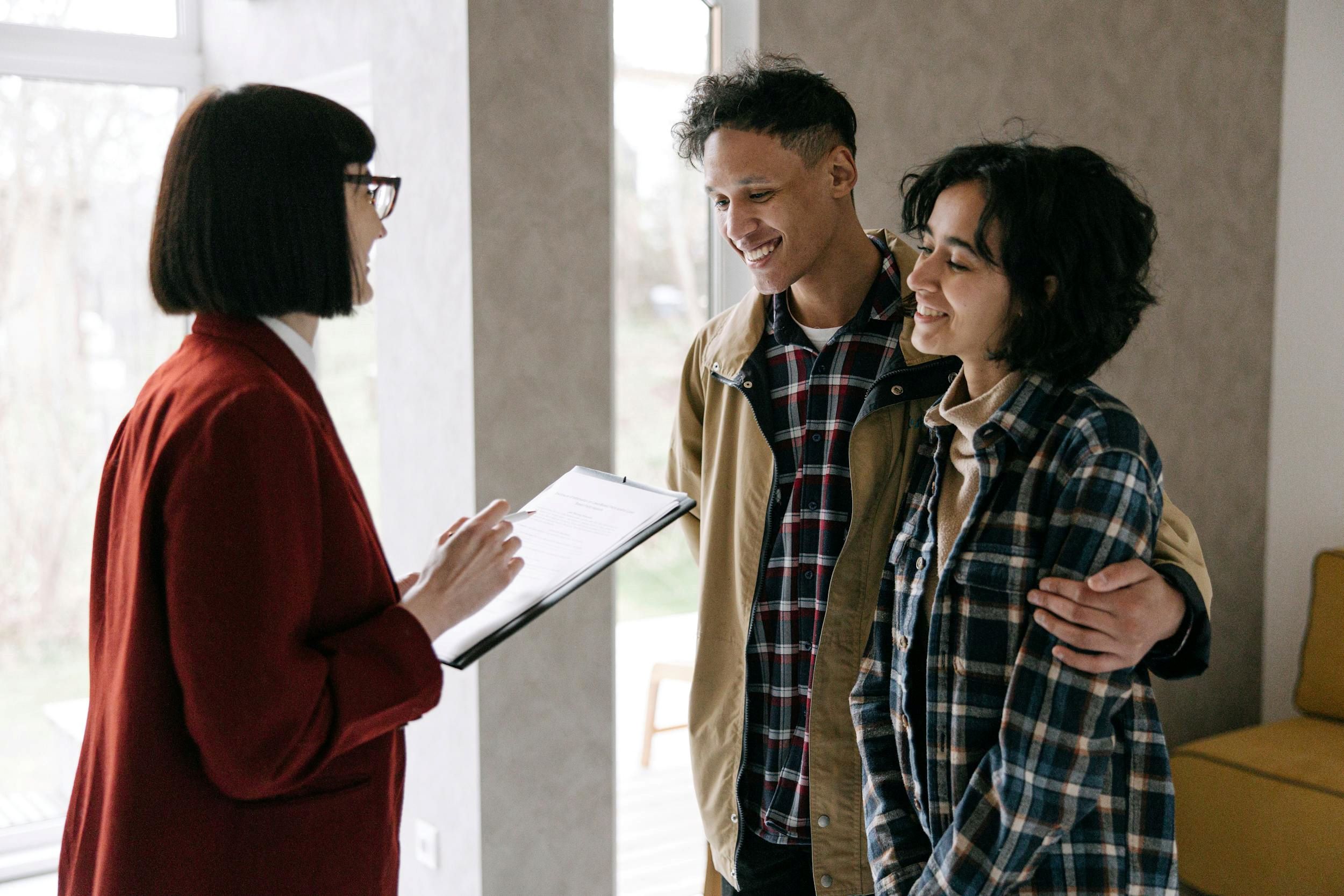 An agent speaks with a couple in a room with oversized windows.