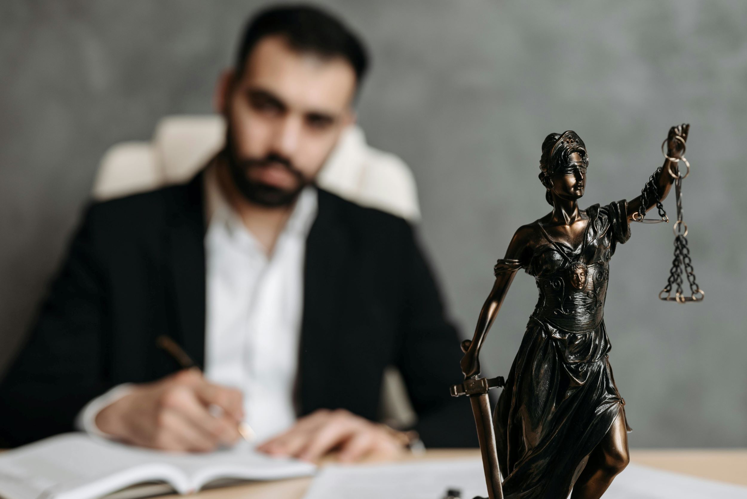 A lawyer sits beside Lady Justice and her scales.