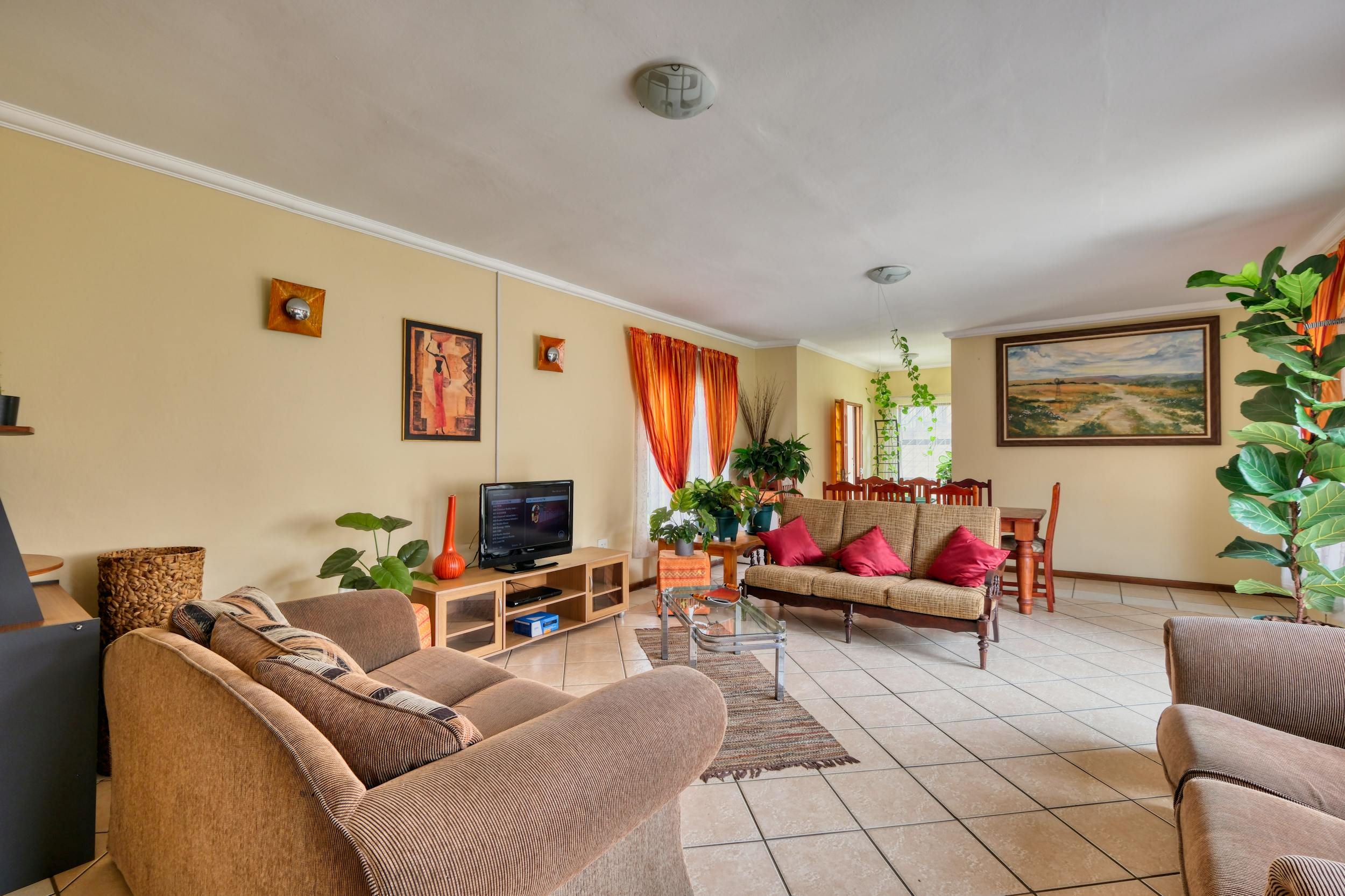An interior image of a living room with brown furniture and orange curtains.