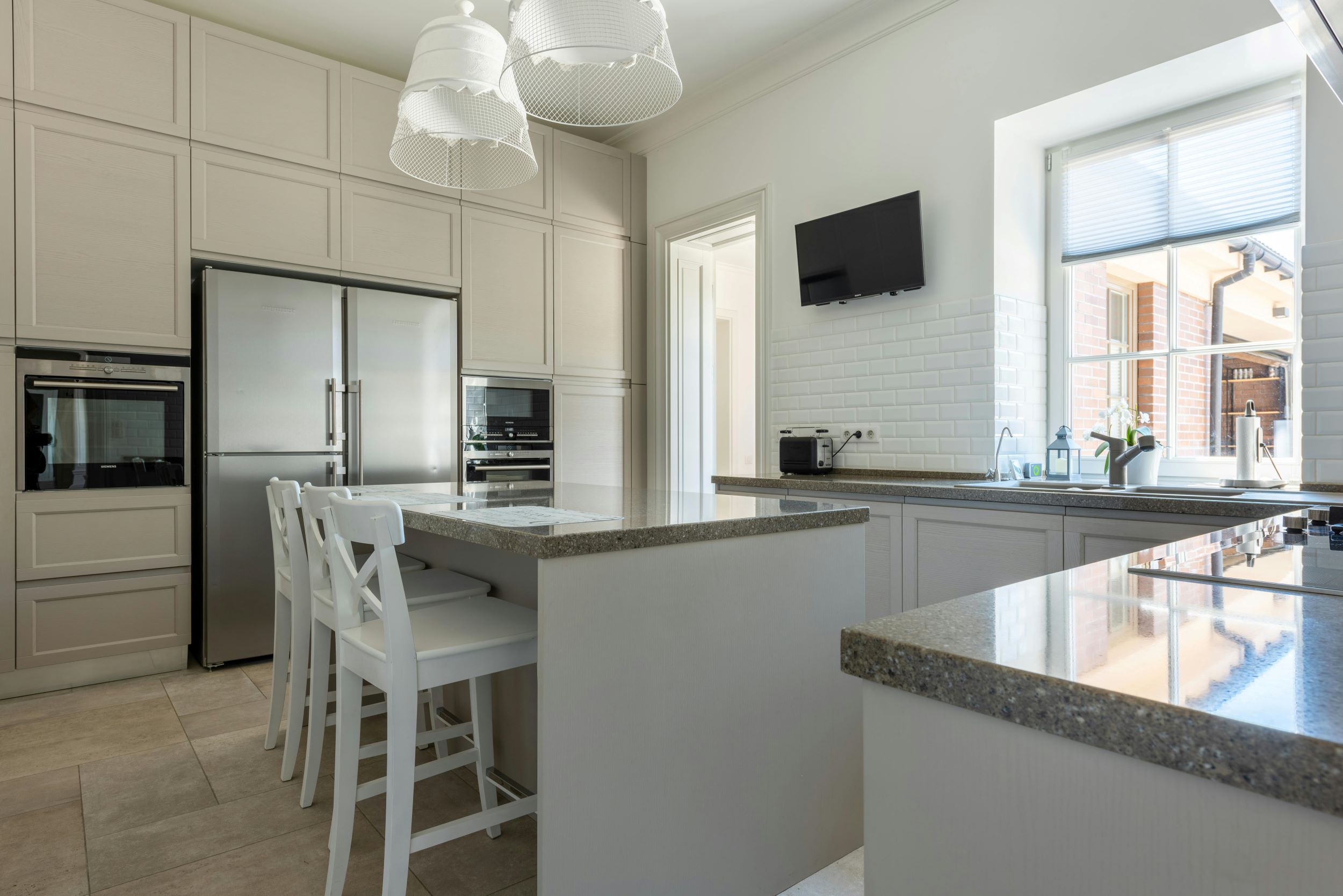 An interior image of a kitchen with white, grey, and beige tones.