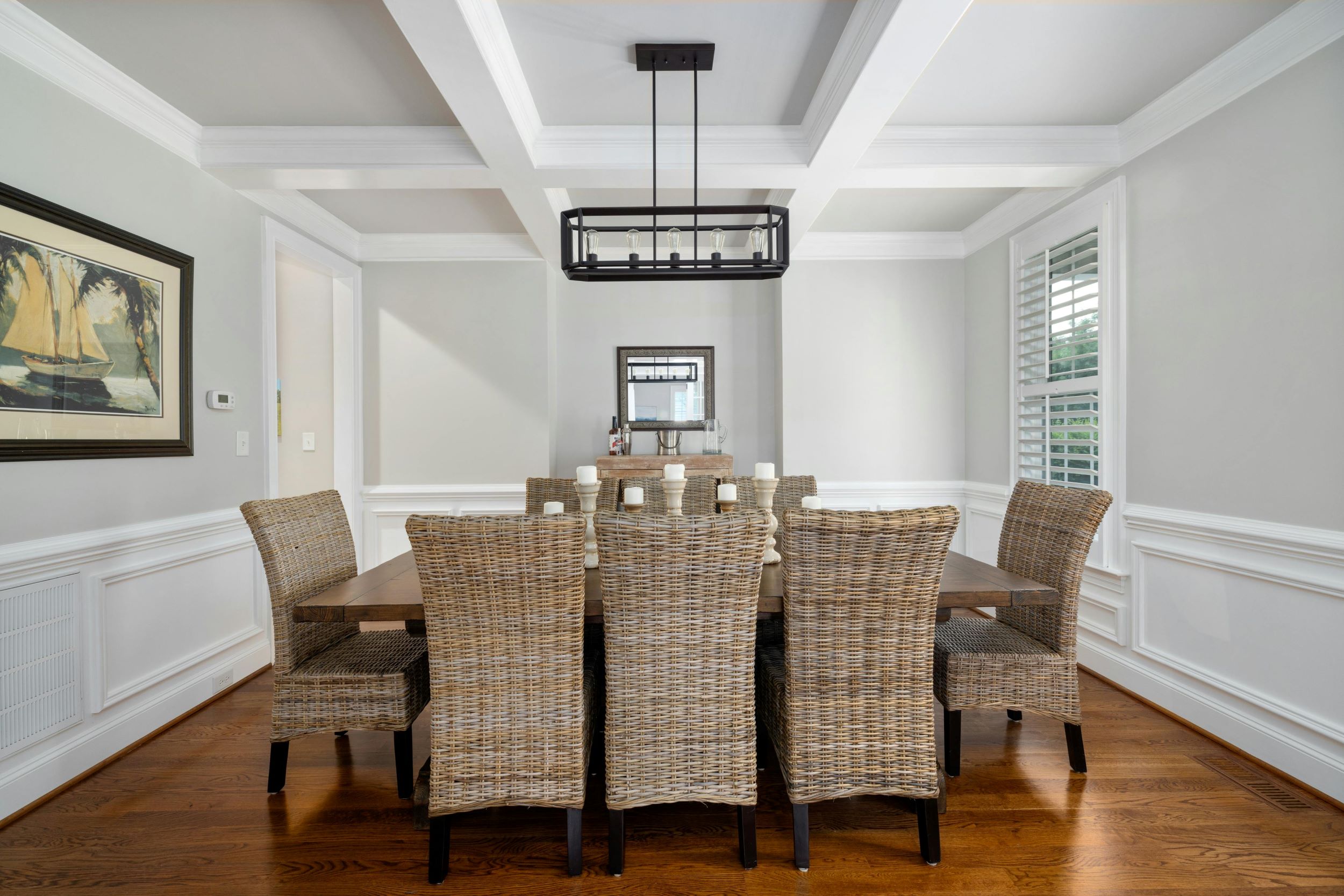 An interior shot of a dining room featuring a brown table and woven chairs.