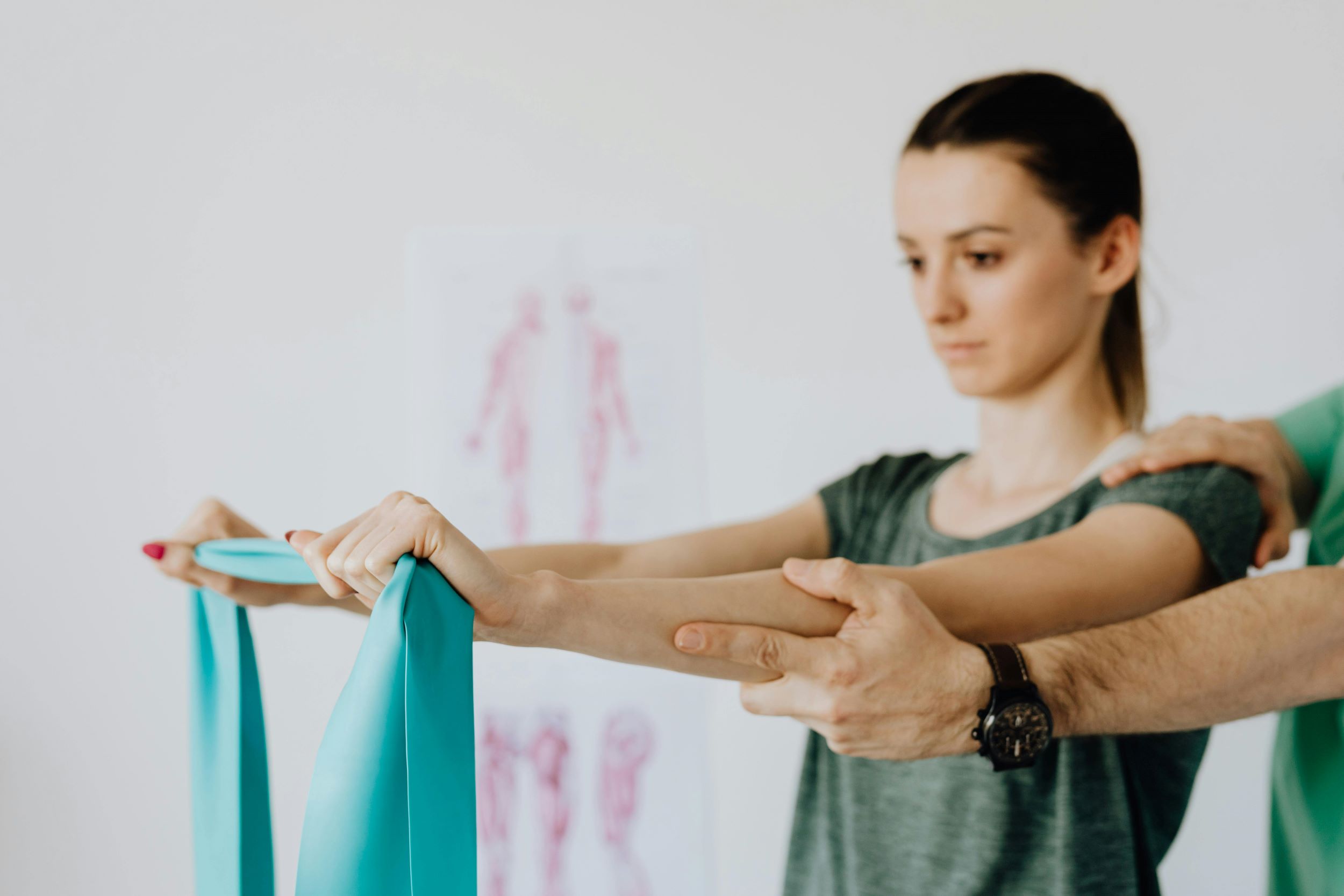 A woman follows guided stretches in front of a white wall.
