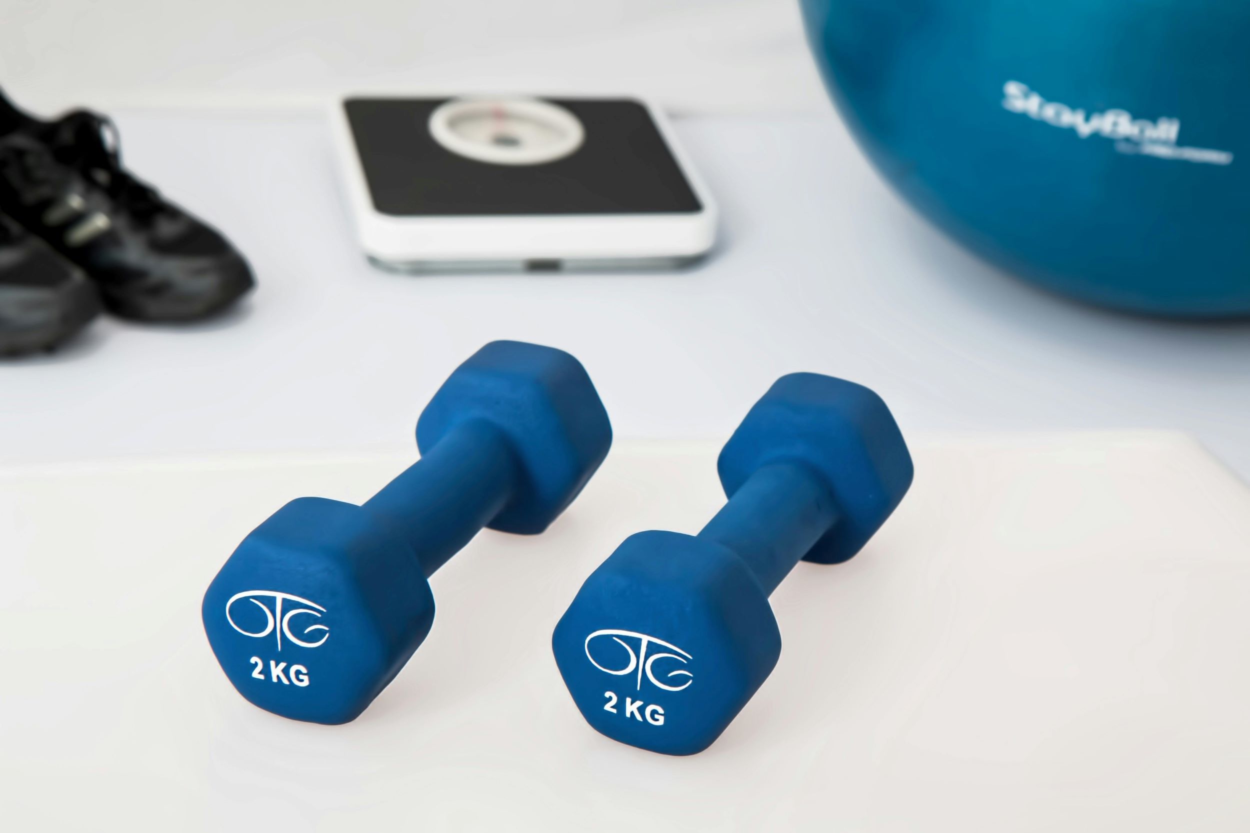 Weights are placed beside a pair of shoes, a scale, and a medicine ball.