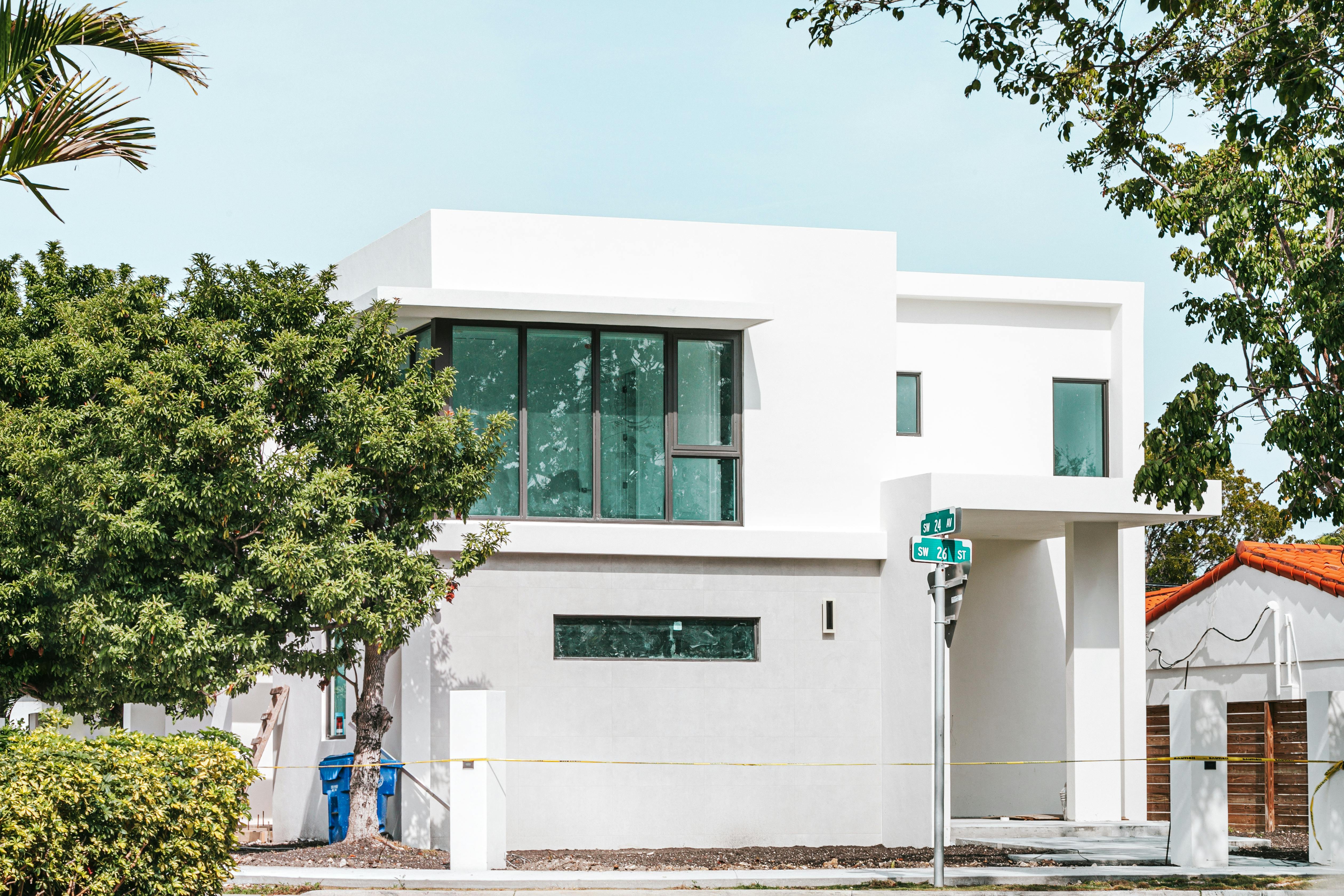 An exterior image of a contemporary home in front of deep green shrubbery.