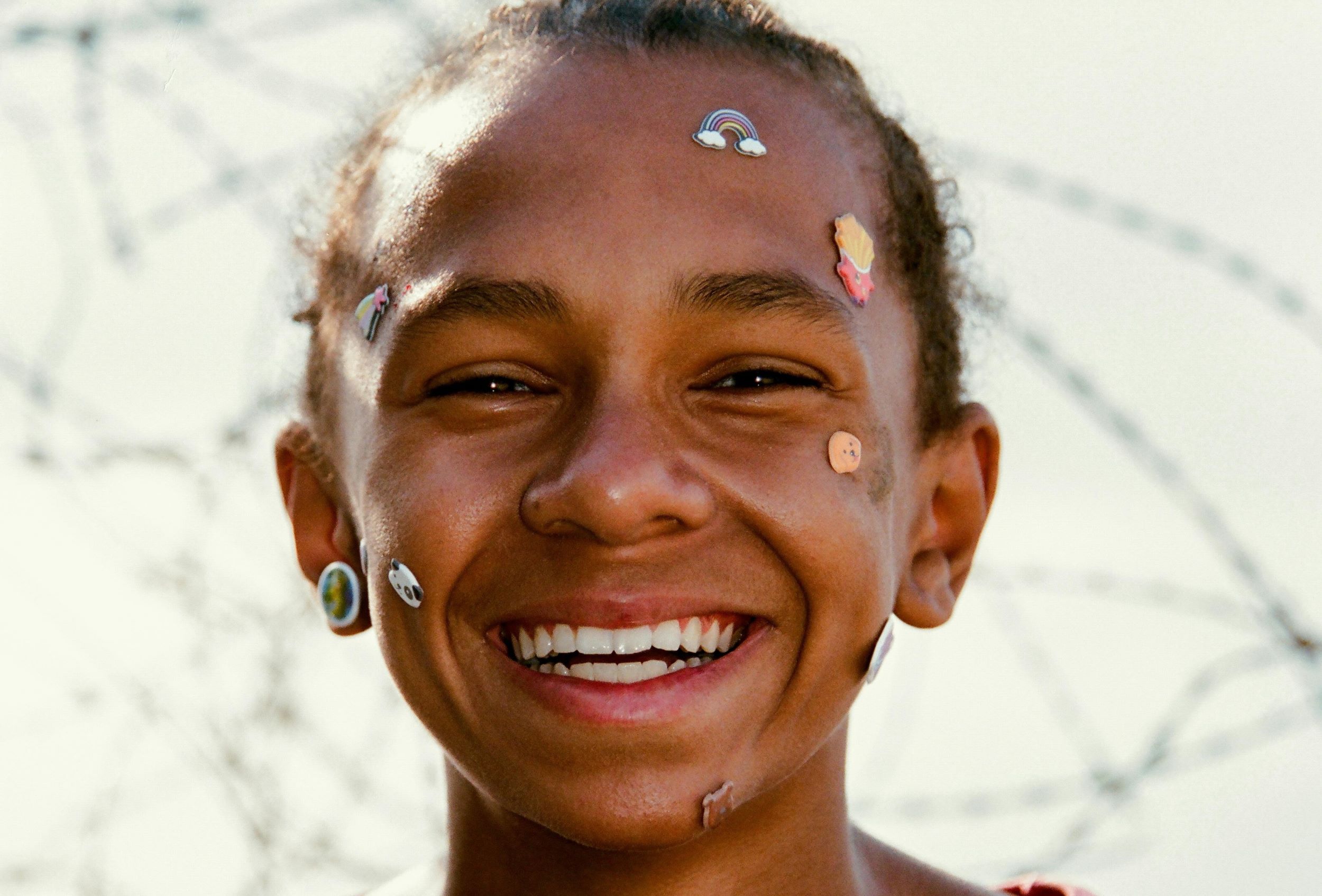 A teenage boy smiles with stickers on his face.