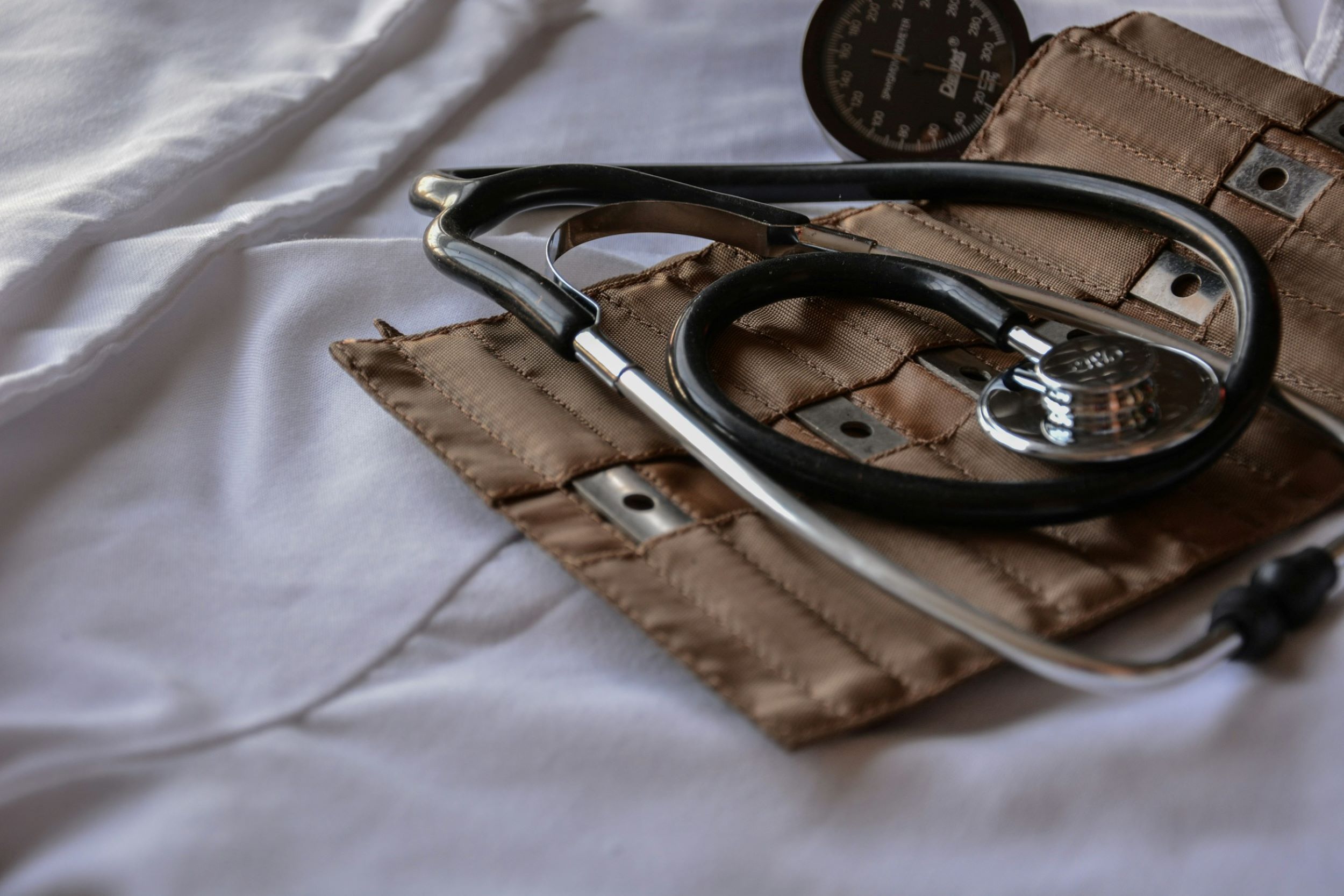 A doctor's stethoscope lays on a patient's bed.