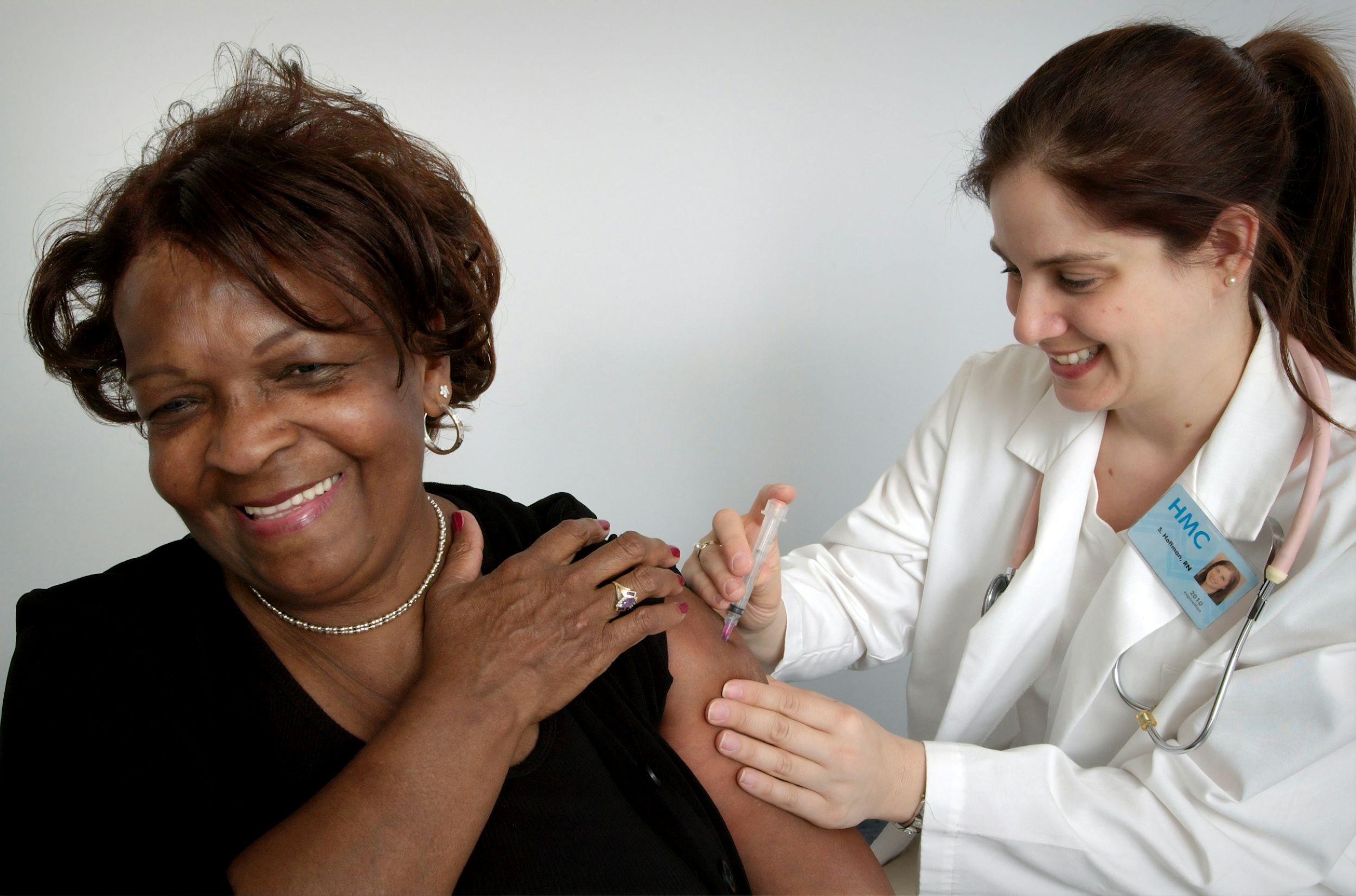 A doctor converses with a patient while administering an injection.