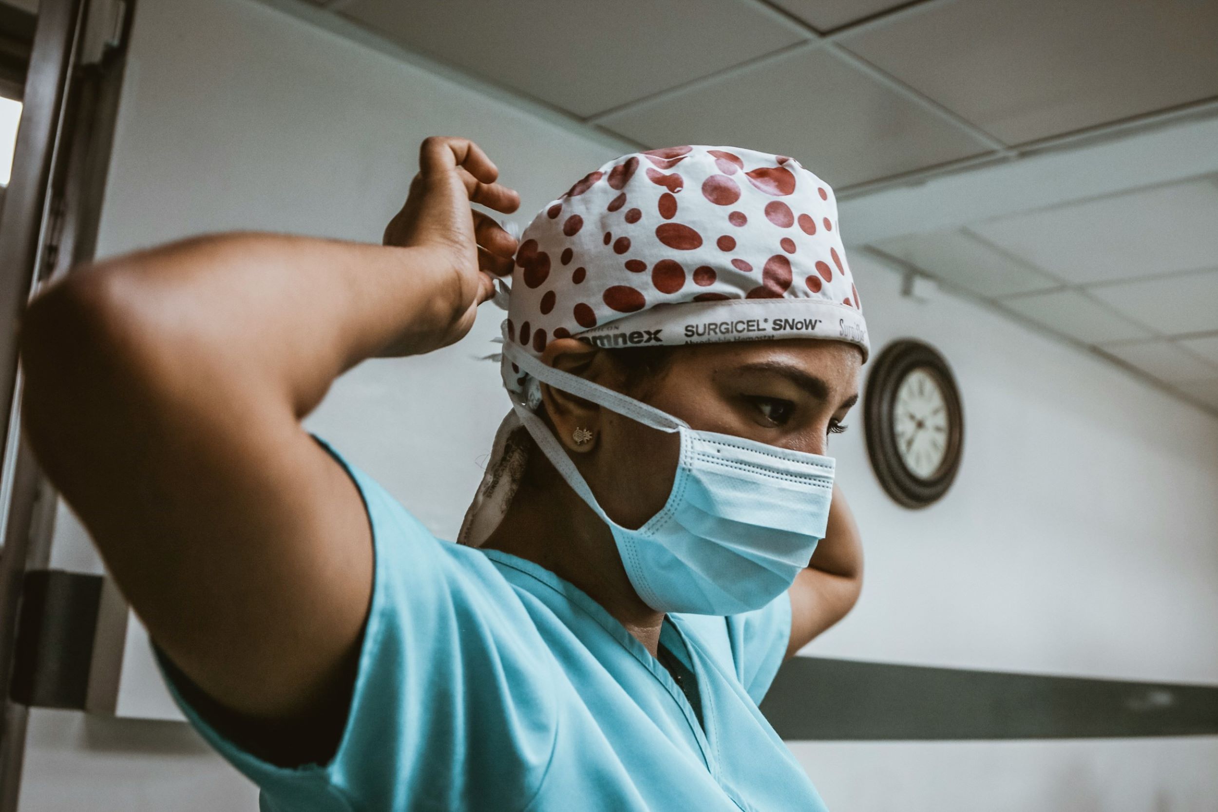 A nurse motions to remove her mask and scrubs.