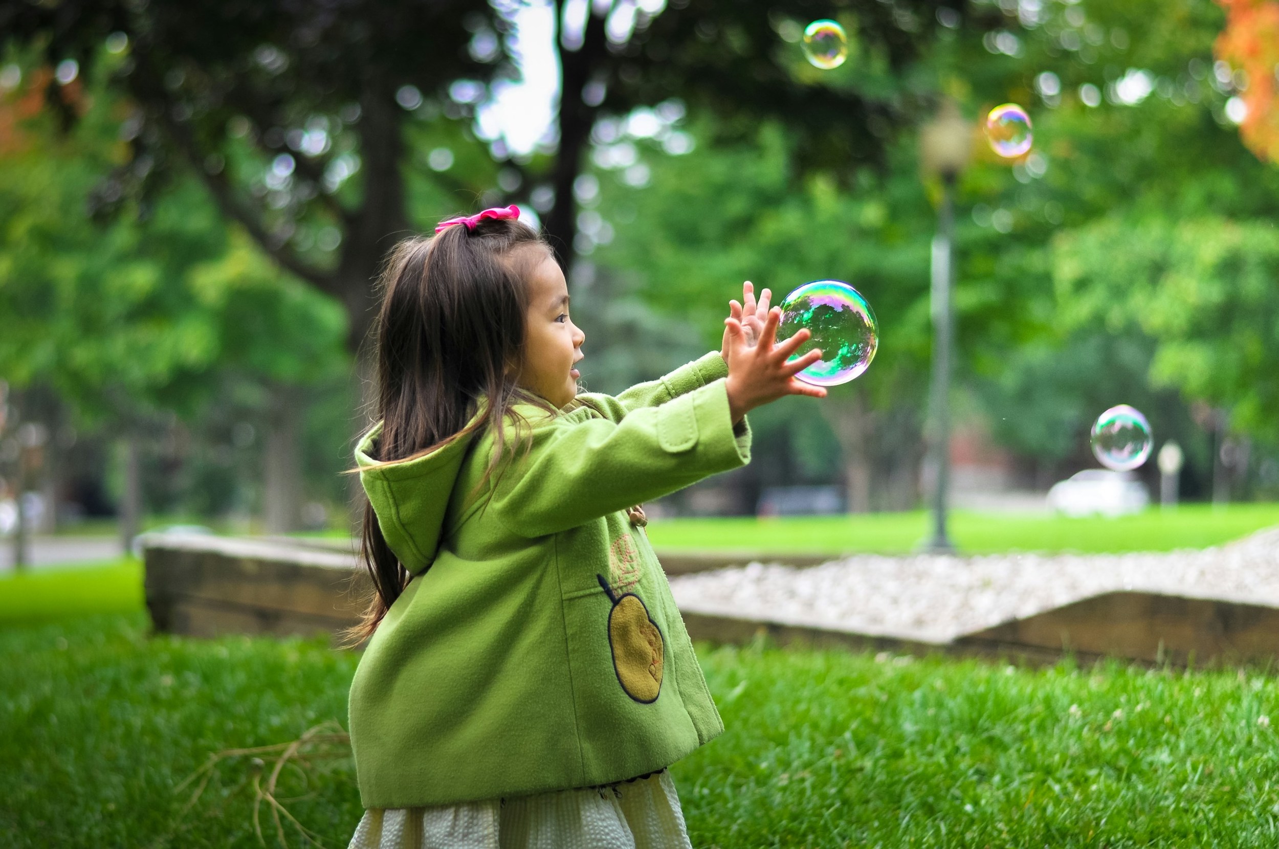 A child clutches an oversized bubble in her hands.