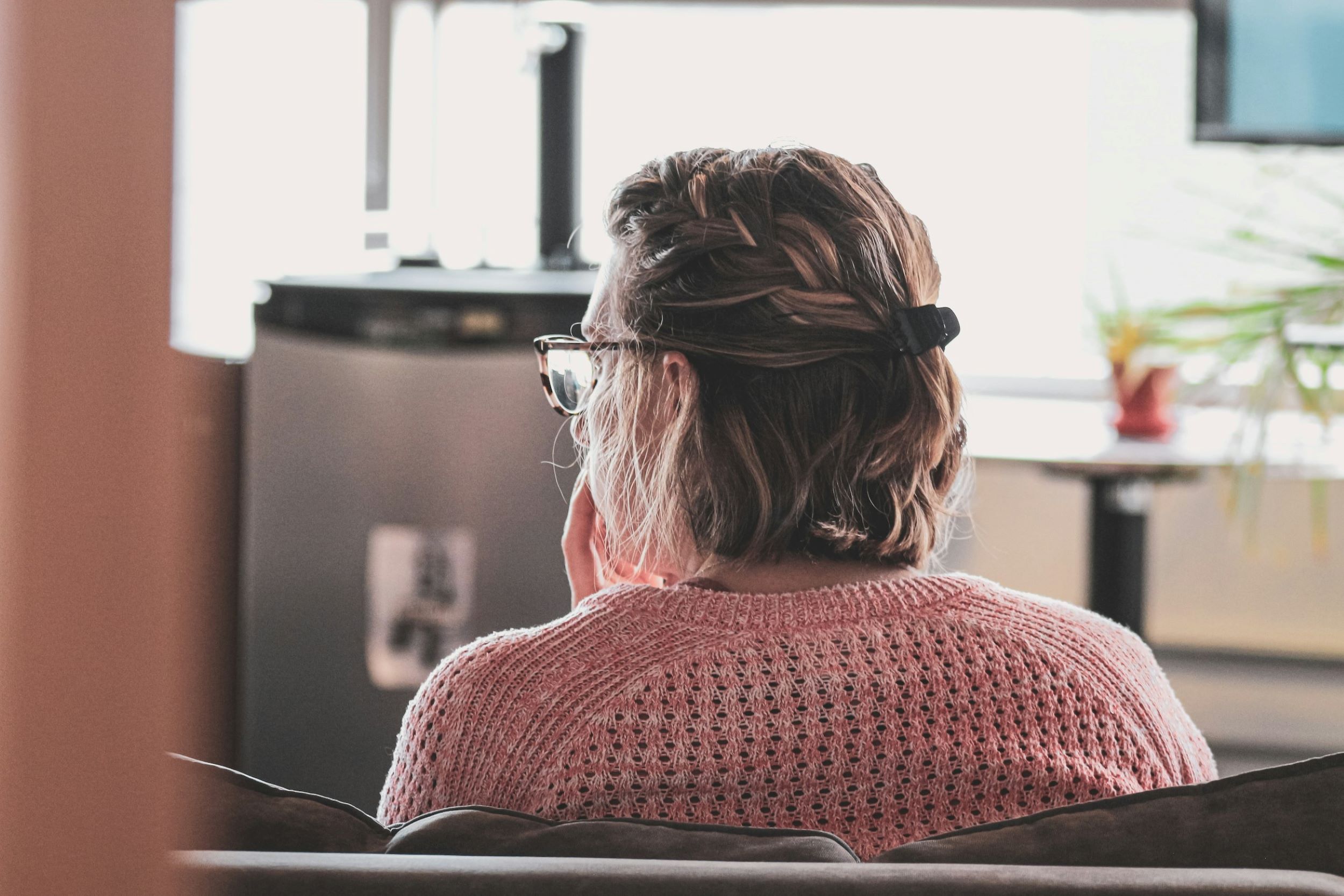 A woman sits in a chair and listens attentively in an office.