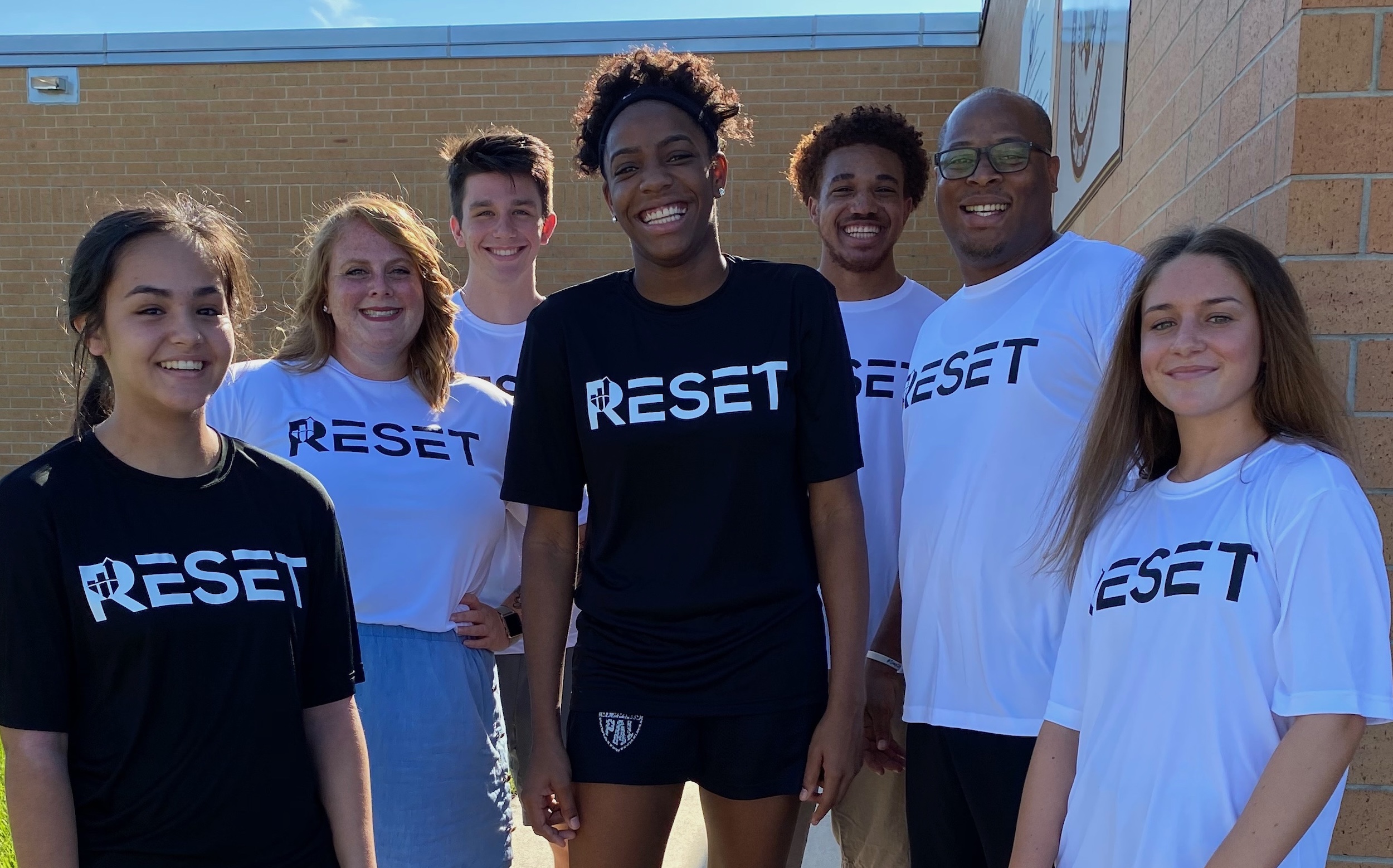 Participants from RESET smile and pose in front of a building.