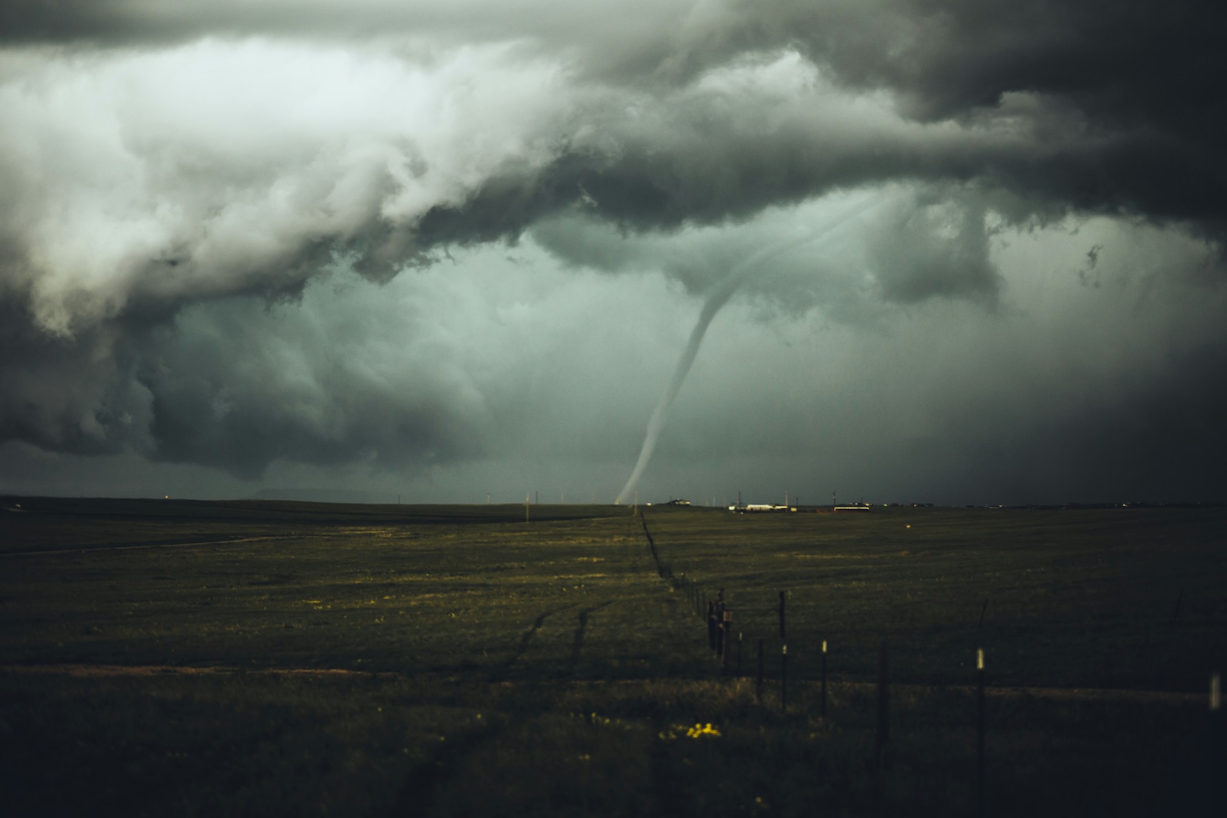 A tornado forms in the sky and moves across flatland.