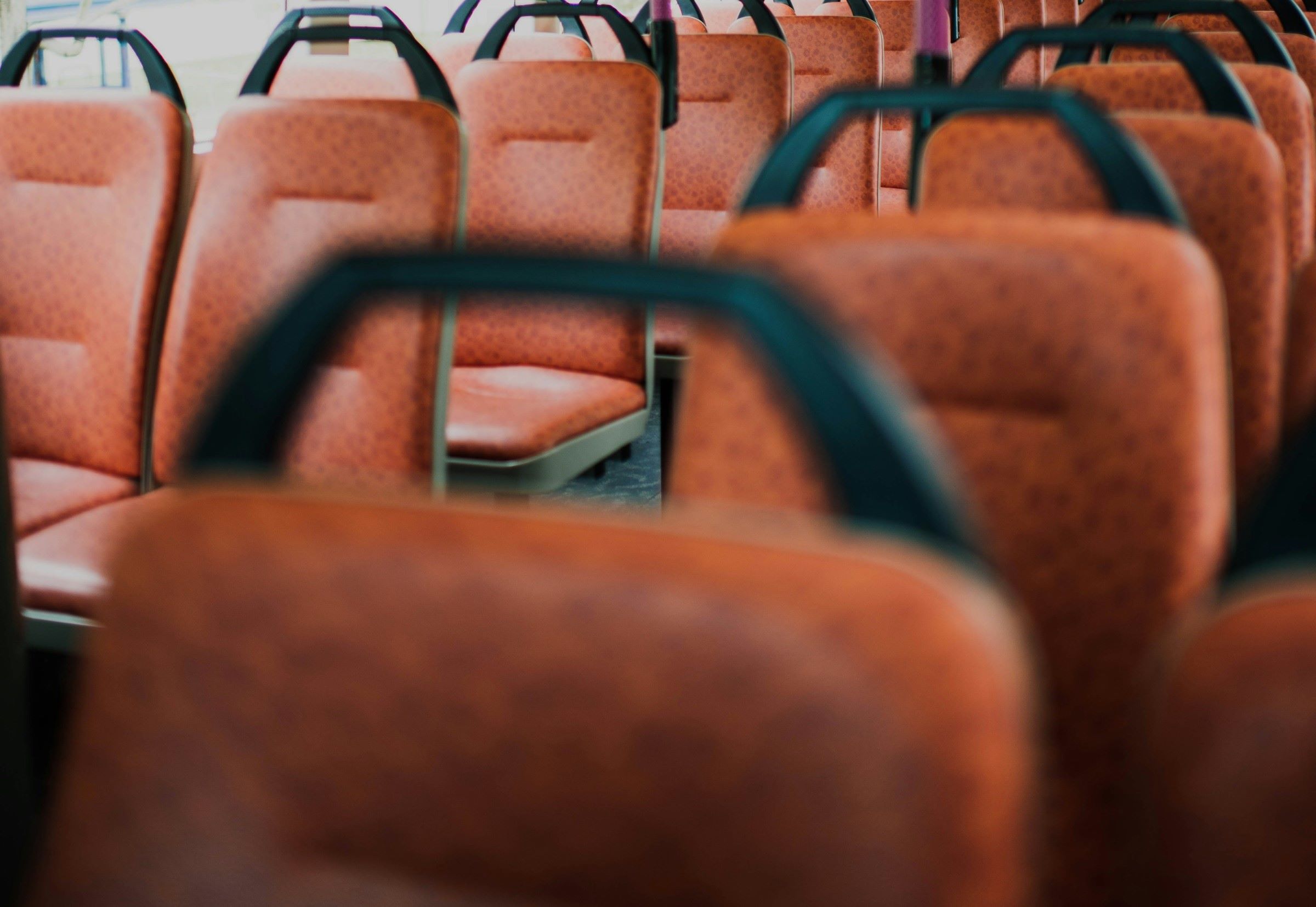 A row of brown seats are arranged neatly inside the bus.