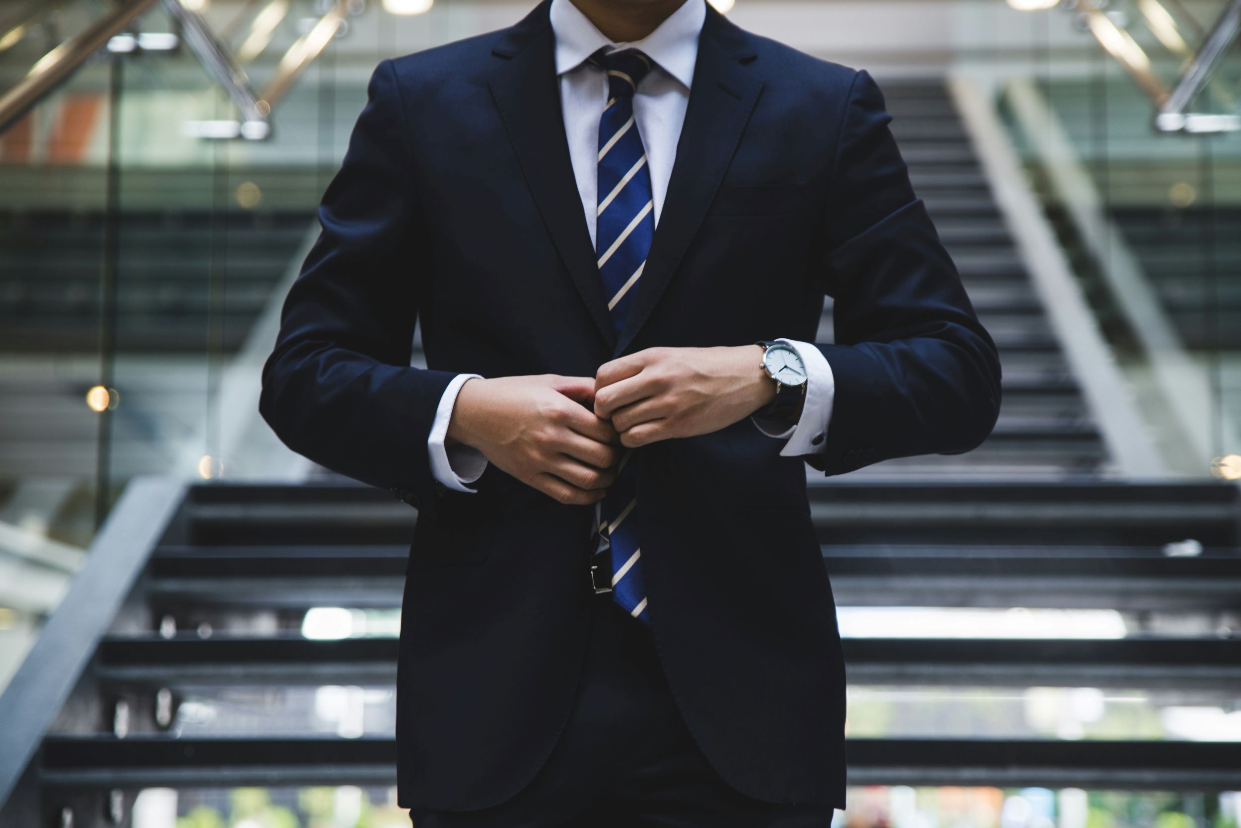 A lawyer descends a staircase while adjusting his blazer.