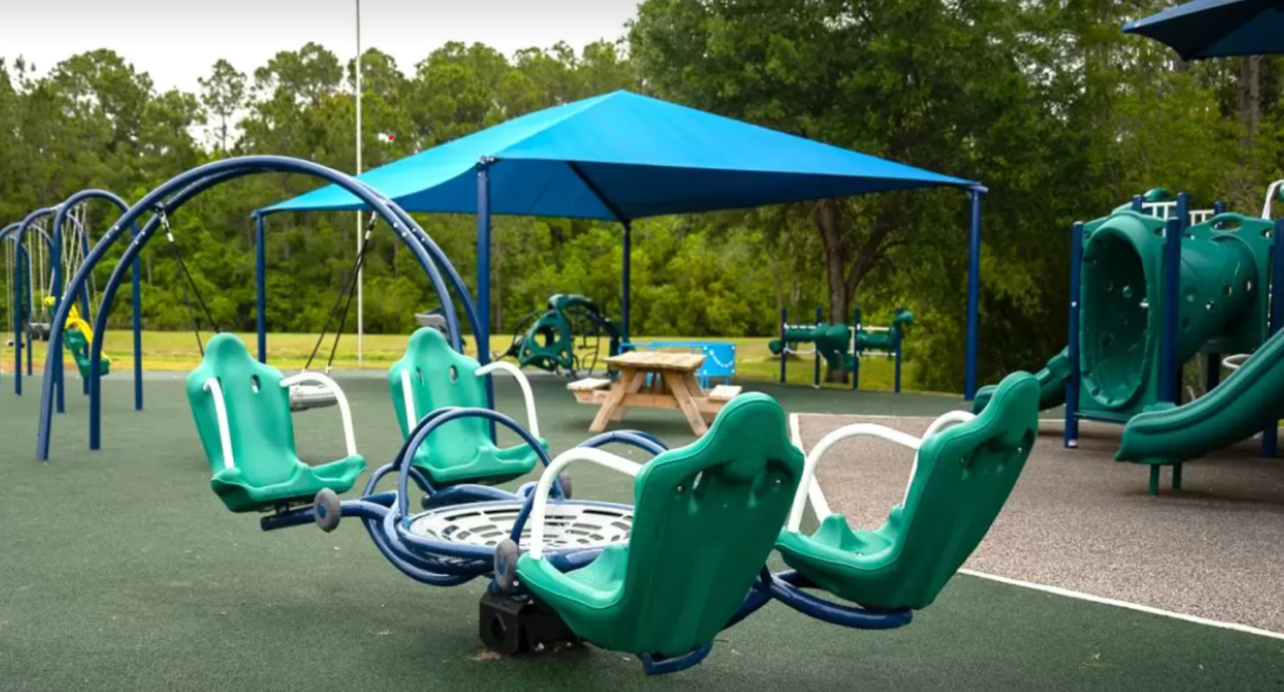 A small playground featuring green safety mats and matching seating areas is located within Aberdeen Park.