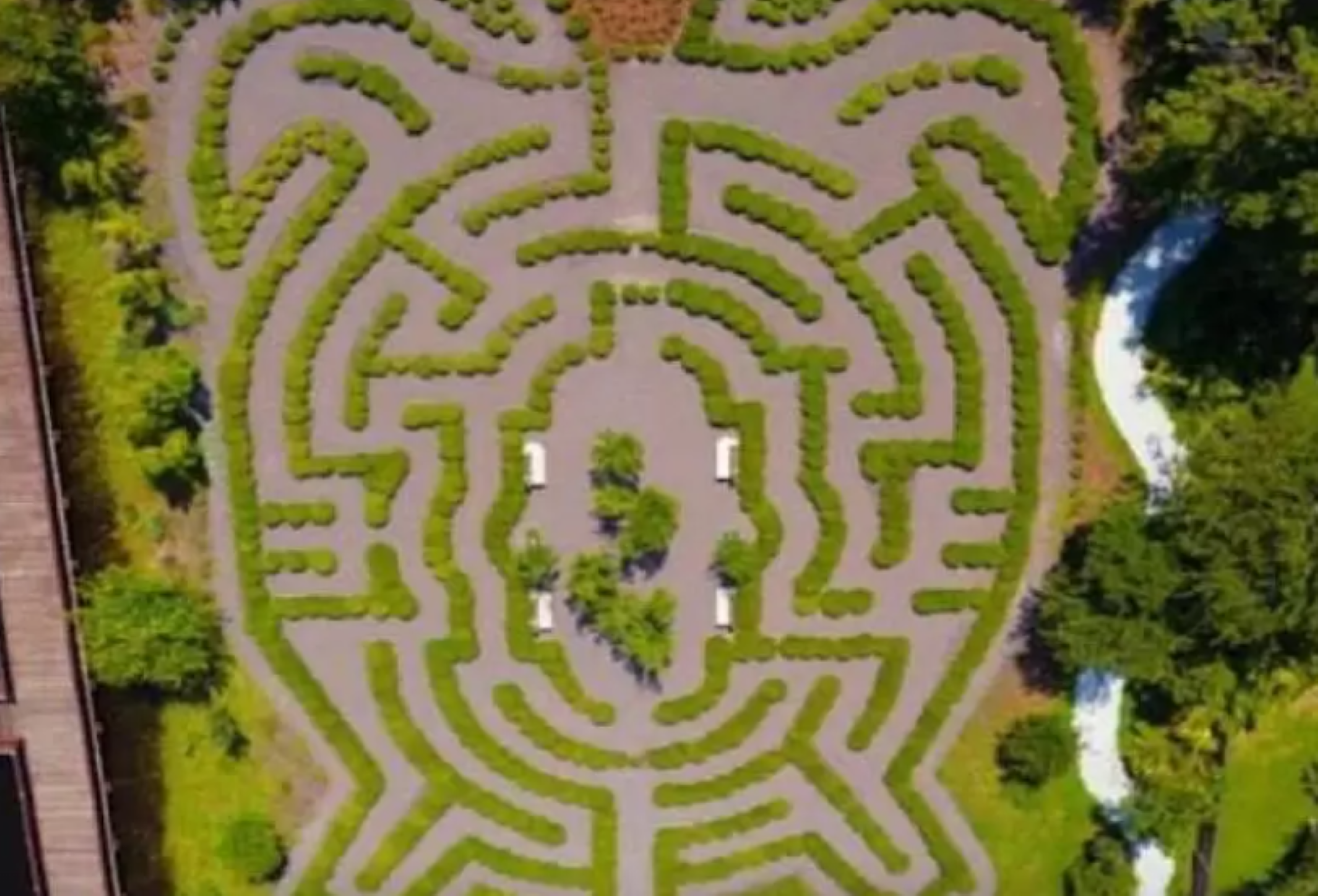 A bird’s-eye view showcases a lush green maze prominently centered in the image.