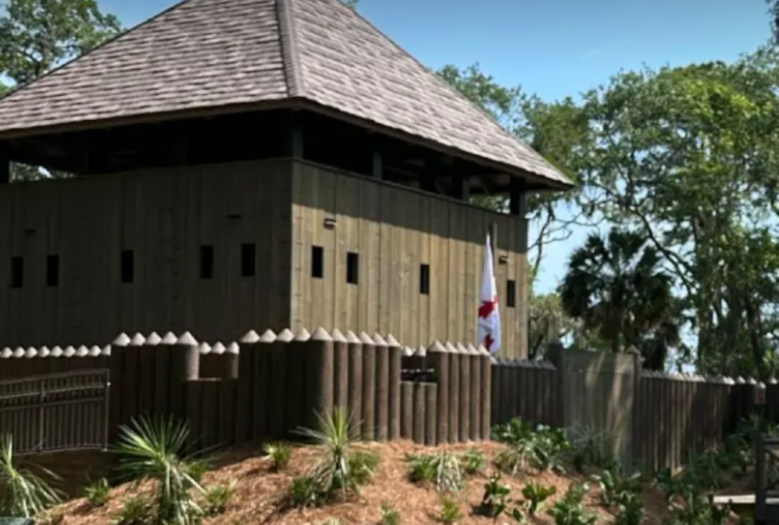 The newly constructed fort at Fort Mose features a footbridge and proudly displays historical flags.