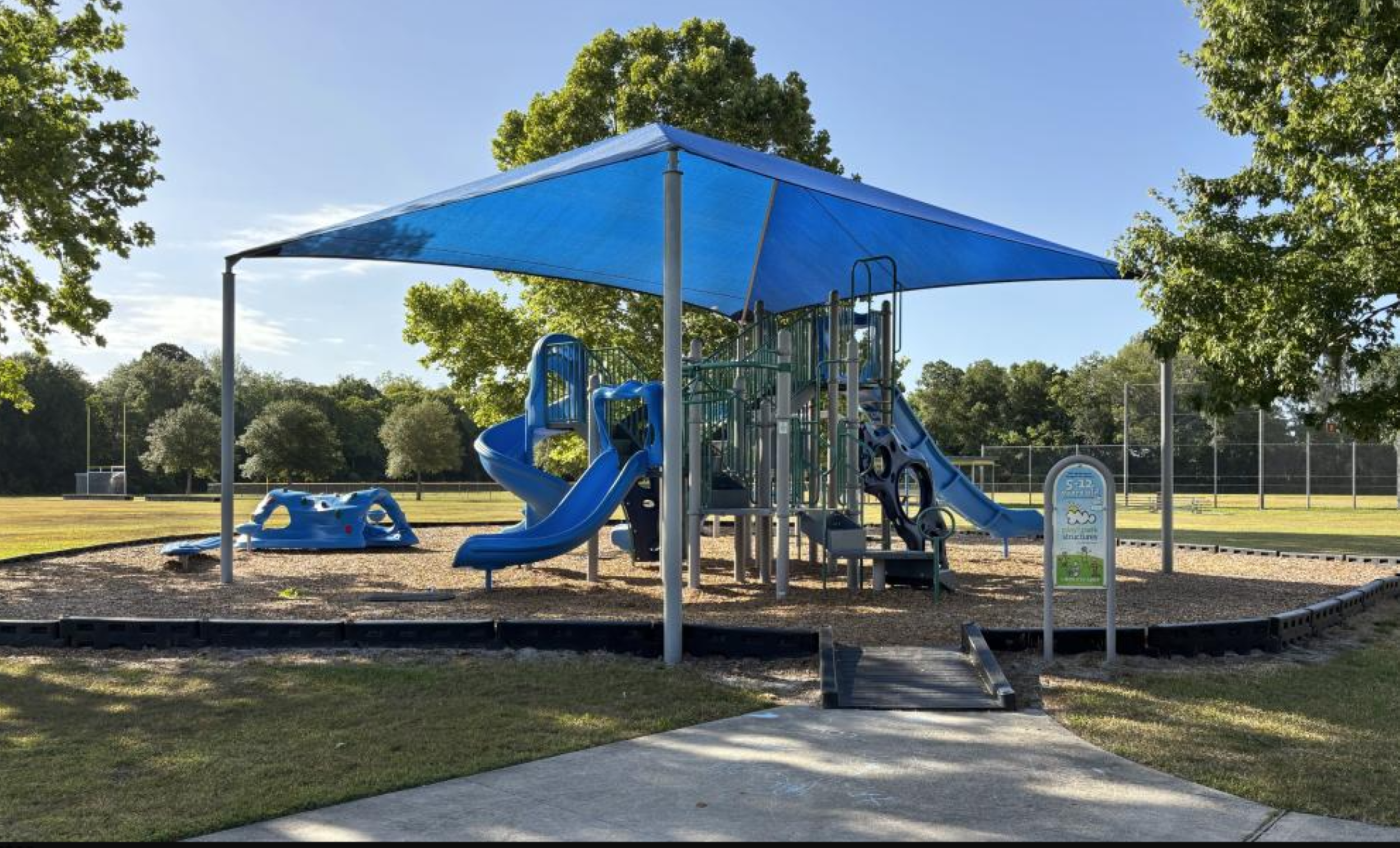 A small playground surrounded by lush green grass sits prominently at the center of the scene.
